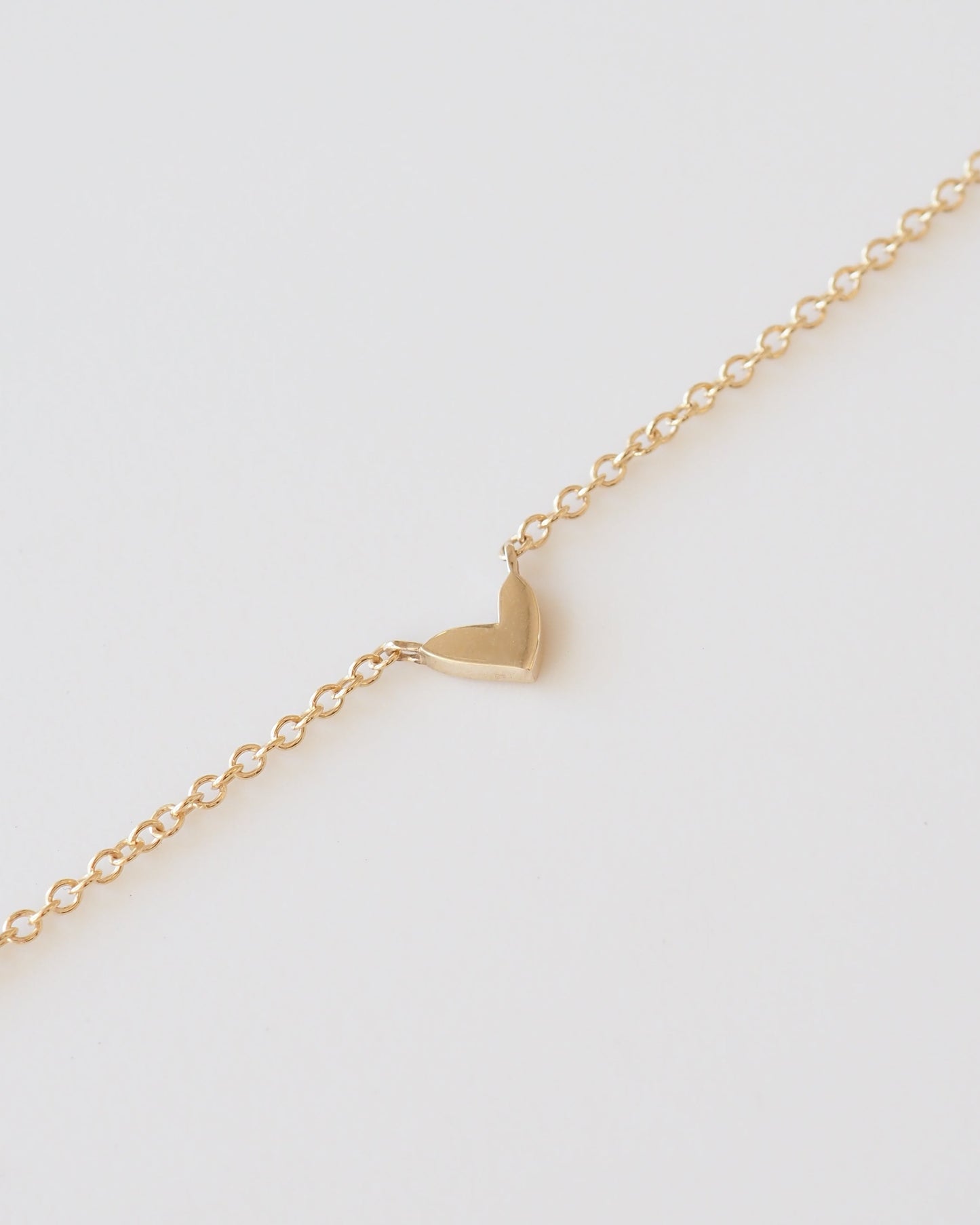 Gold heart-shaped pendant on a gold chain against a white background