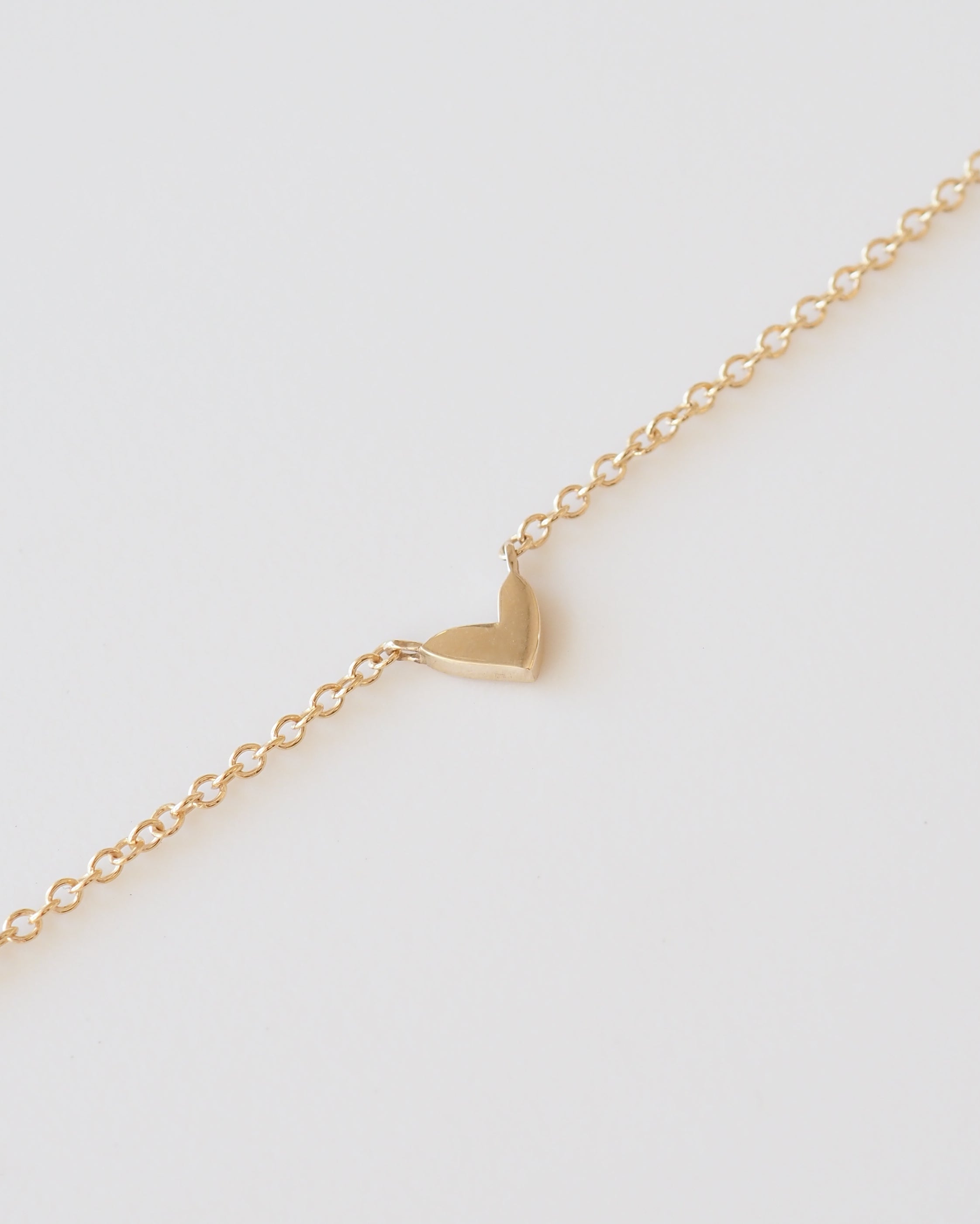 Gold heart-shaped pendant on a gold chain against a white background