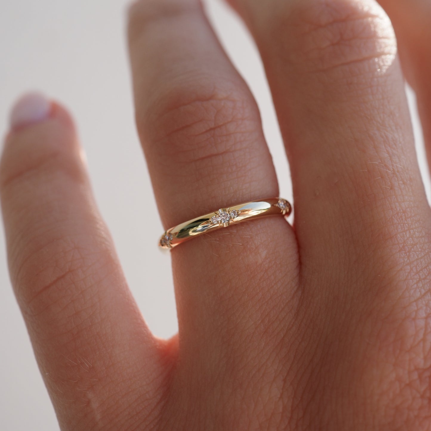 A gold ring with a small central diamond worn on a person's finger, showcasing elegant and minimalist luxury jewellery.
