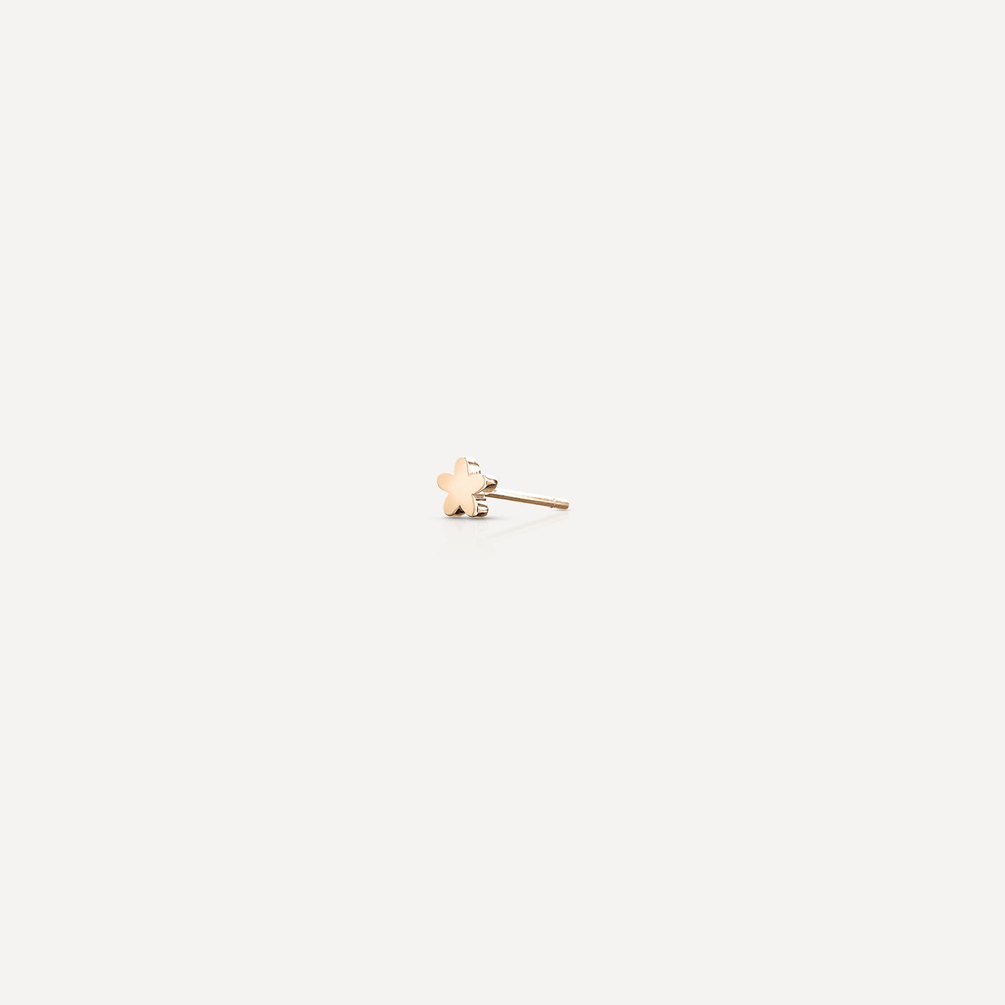 Delicate gold stud earring with a clover design on a plain white background, highlighting luxury jewellery details.