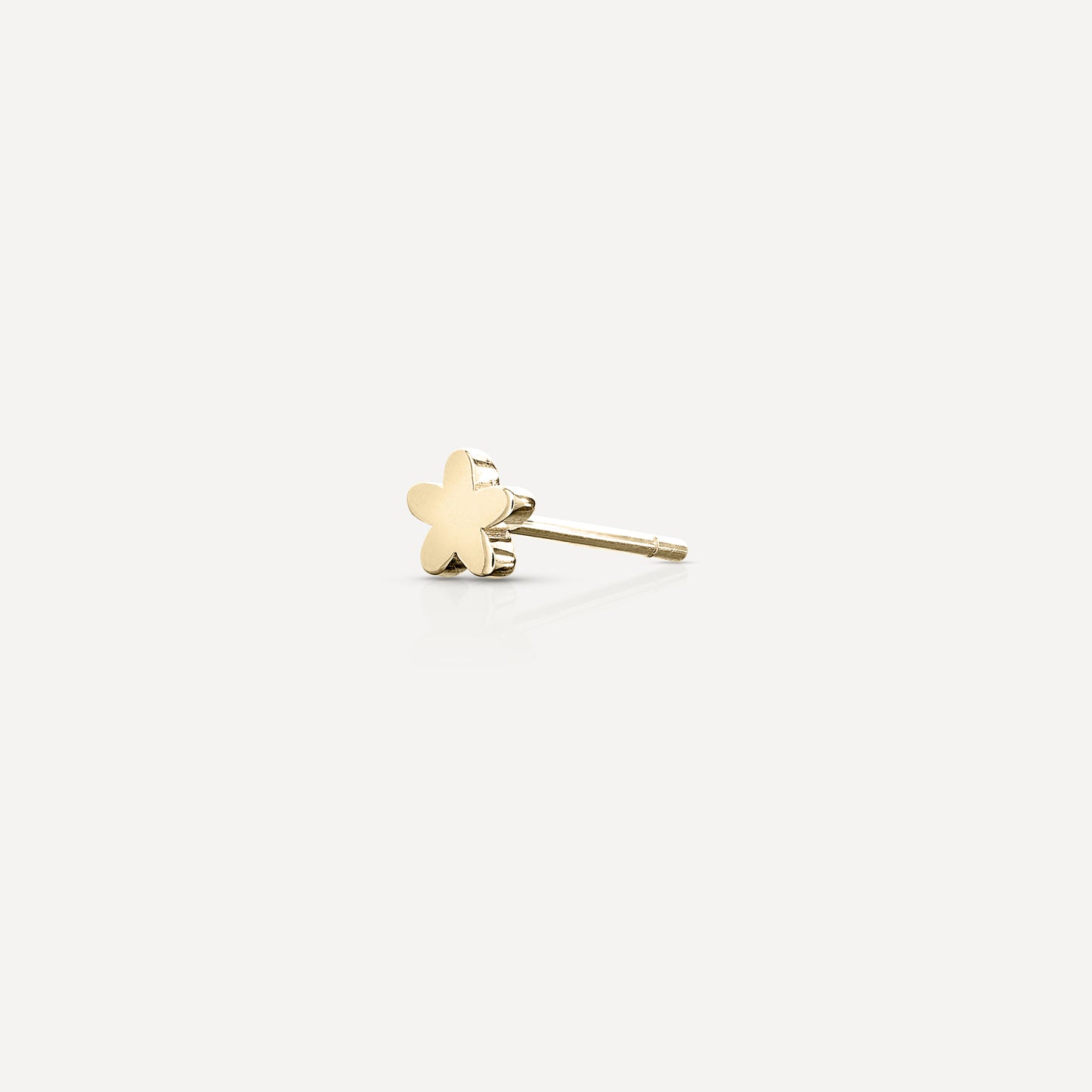 Gold star-shaped earring on a light background, showcasing minimalist luxury jewellery design. Perfect for elegant fashion statements.