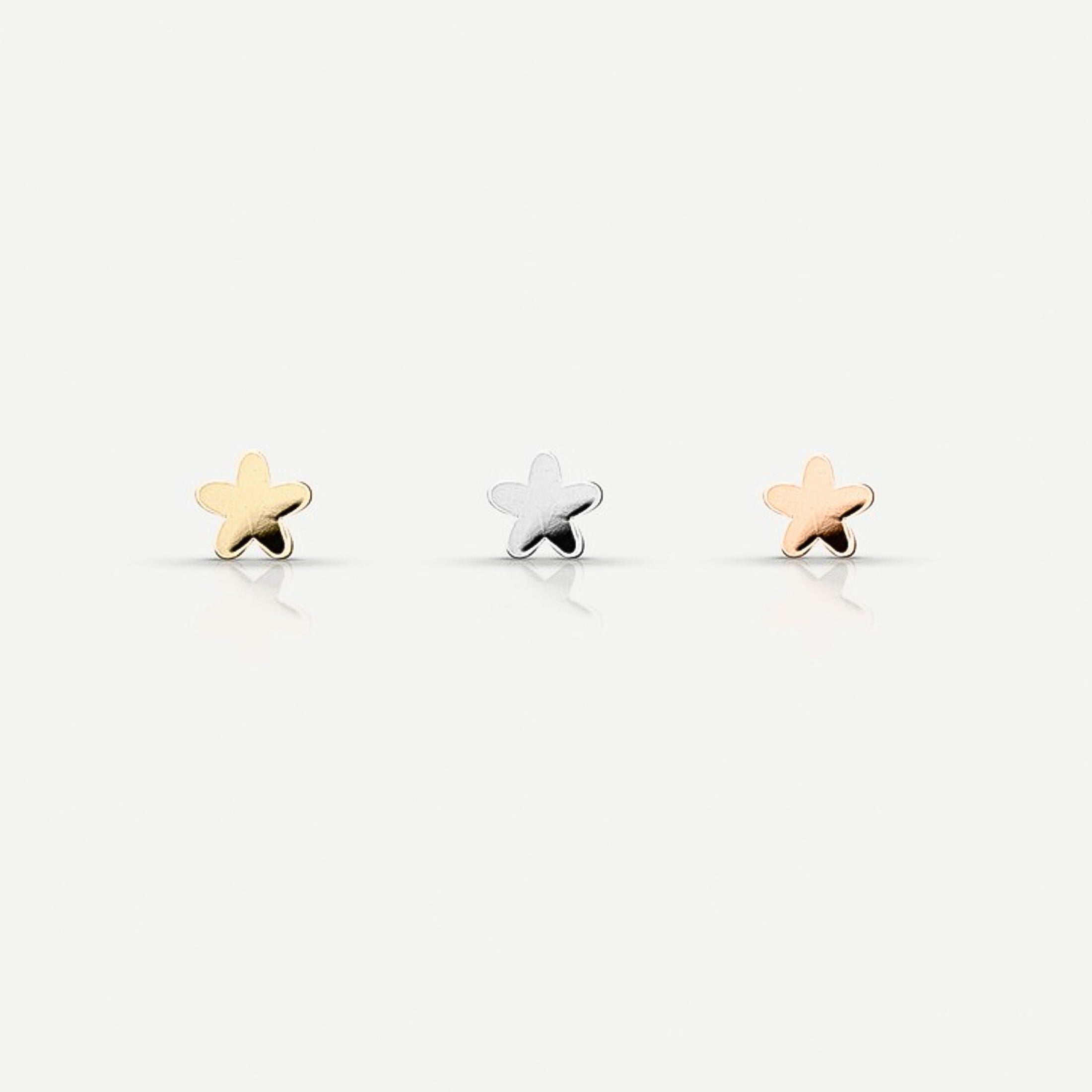 Three star-shaped stud earrings in gold, silver, and rose gold tones are arranged in a row against a light background.