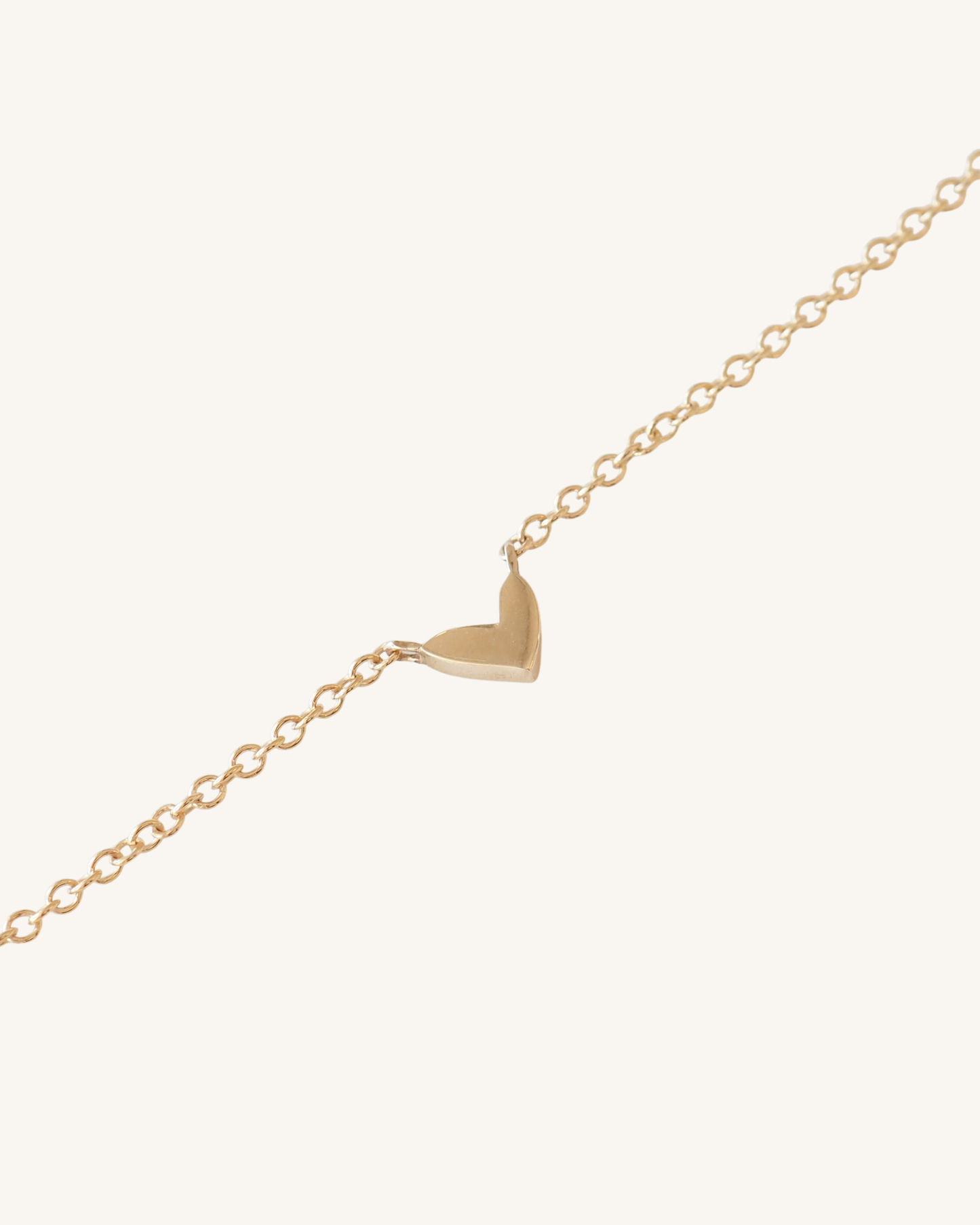 Gold heart-shaped pendant on a chain against a white background