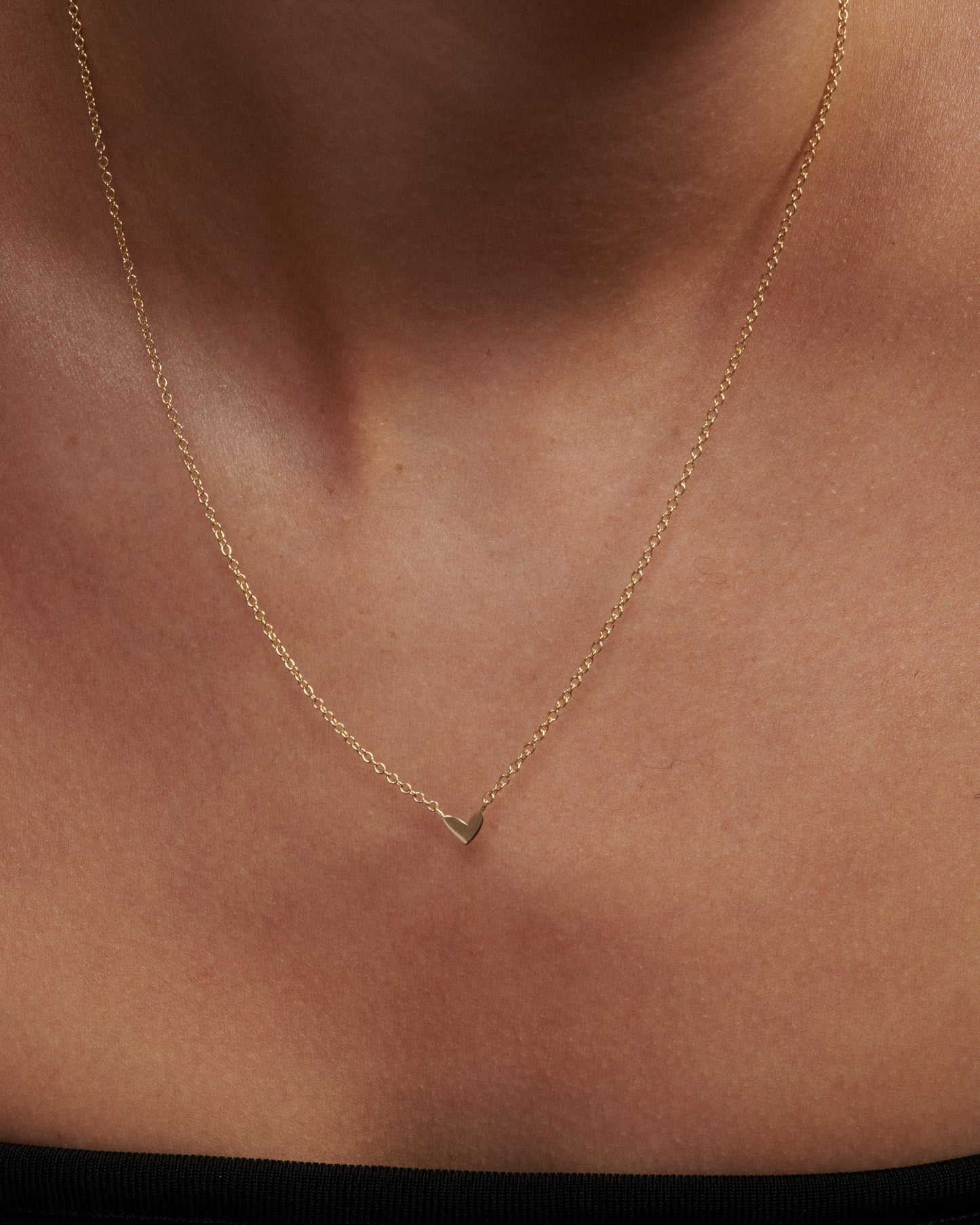 Gold necklace with a heart pendant on a person's neck