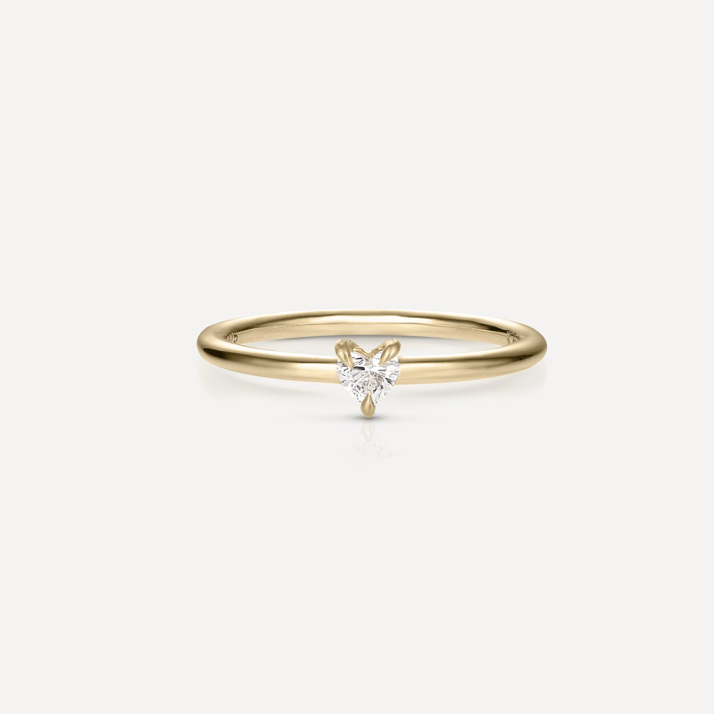 Gold ring with a heart-shaped diamond solitaire on a thin band, set against a plain white background. Elegant and minimalist jewellery design.