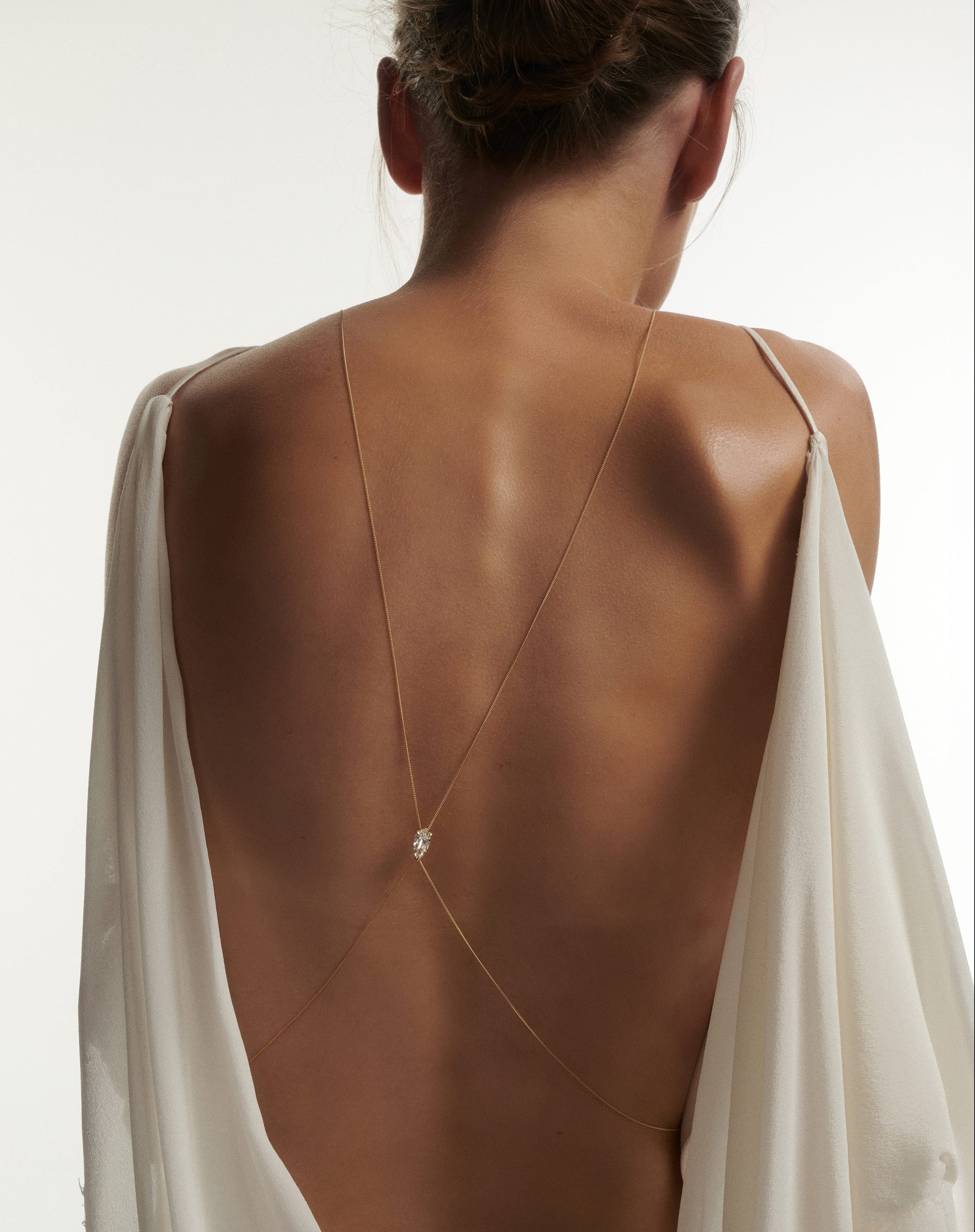 Woman wearing a backless dress with a white overlay on a plain background with Diamond Lariat Body Chain