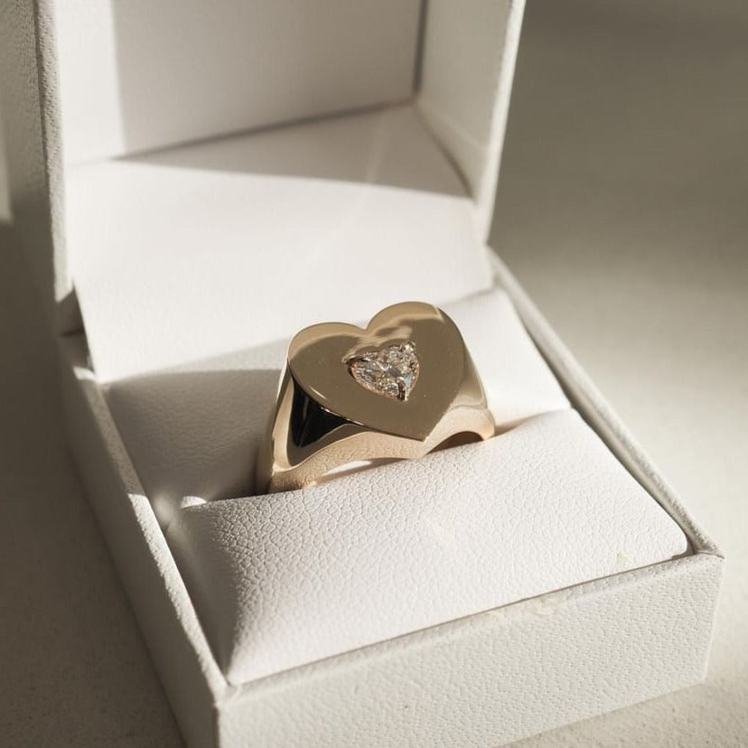 Gold heart ring with diamond accent in a white jewellery box, reflecting luxury and elegance. Perfect for special occasions or gifts.
