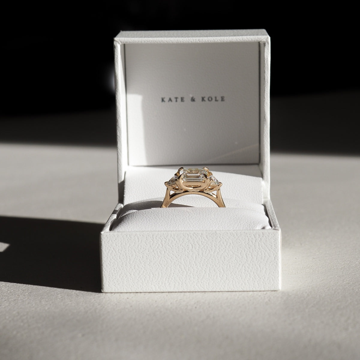 Isla showcases the timeless beauty of a 1.27ct emerald & trillion trilogy lab-grown diamond ring set in solid 18ct yellow gold. 