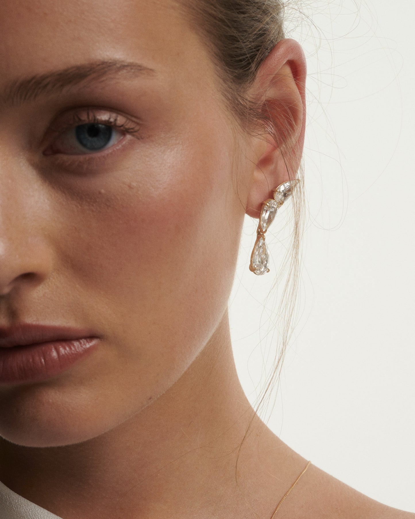Close-up of a woman wearing a sparkling earring against a neutral background