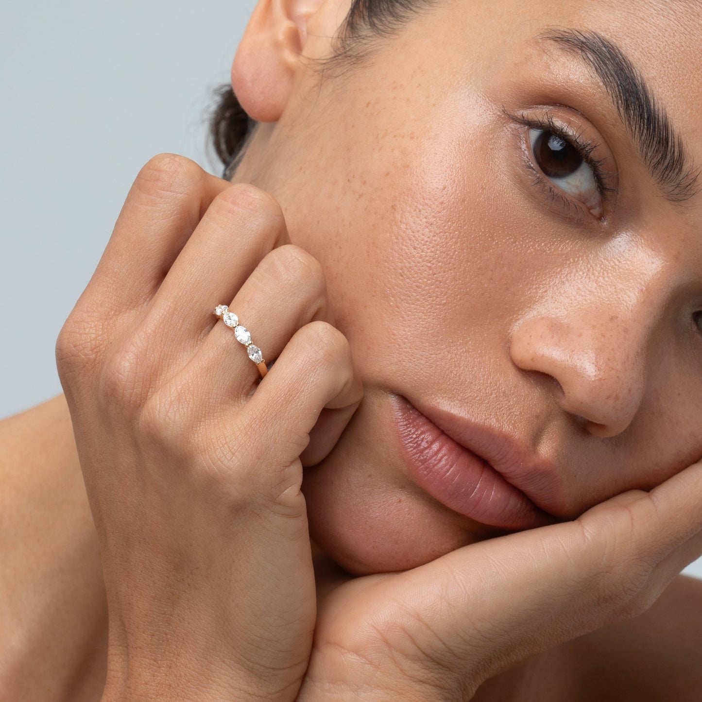 Woman with a diamond ring on her finger against a neutral background