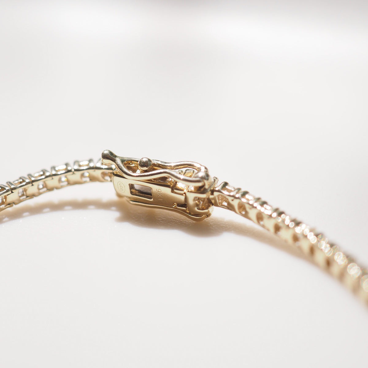 Diamond bracelet on a white surface with a neutral background