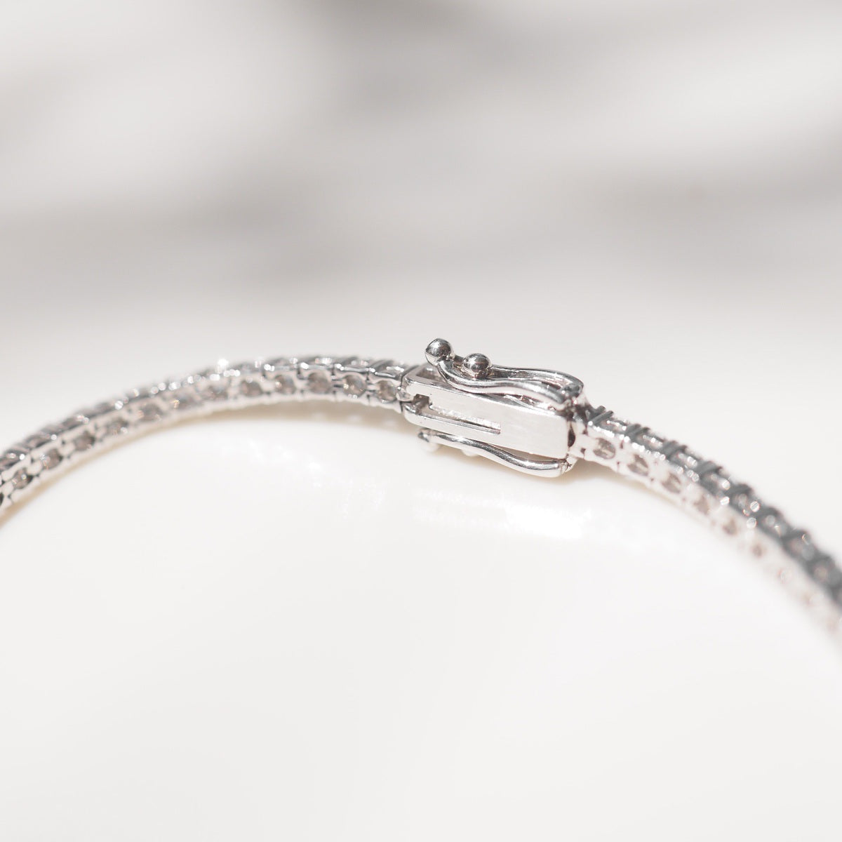Diamond bracelet on a white surface with a neutral background