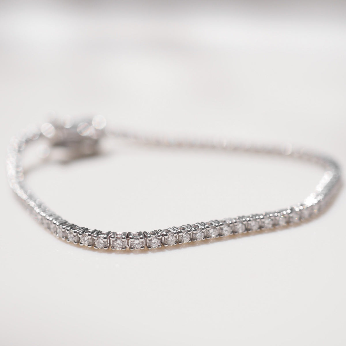 Silver bracelet with small diamonds on a light gray background