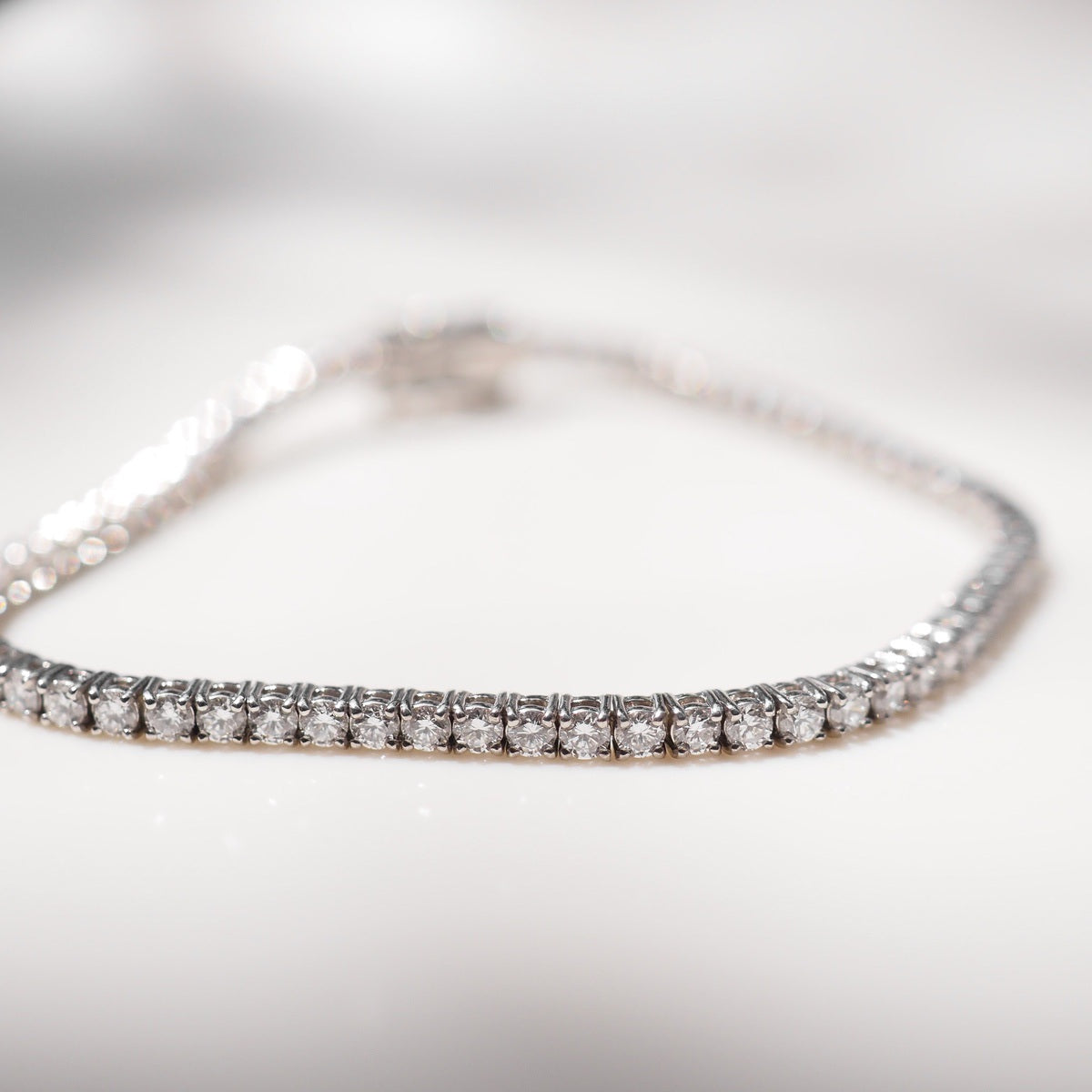 Diamond bracelet on a white surface with a neutral background