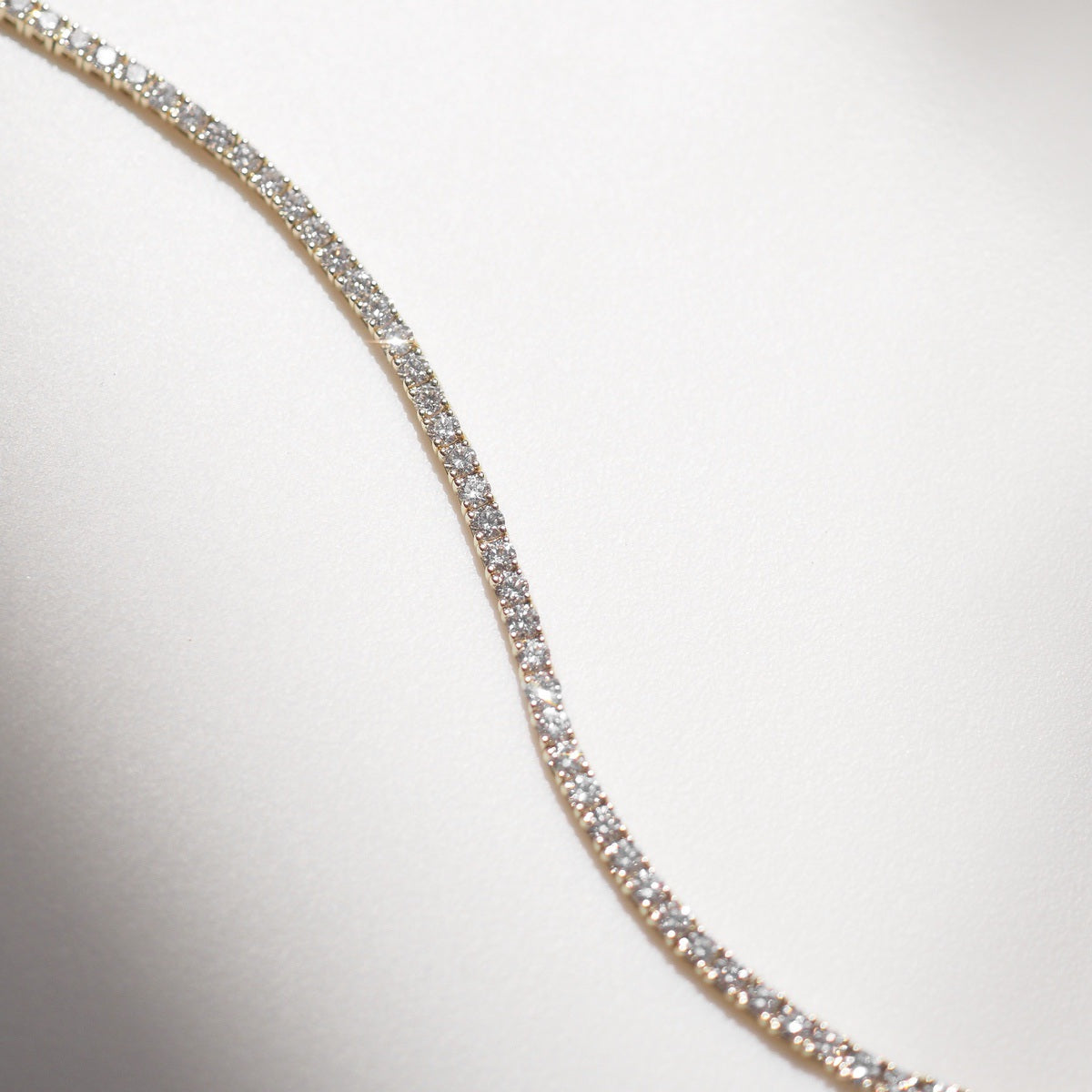 Diamond bracelet on a white surface with a neutral background