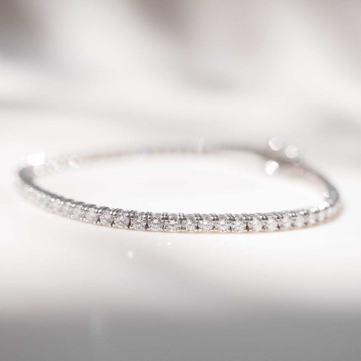 Diamond bracelet on a white surface with a neutral background