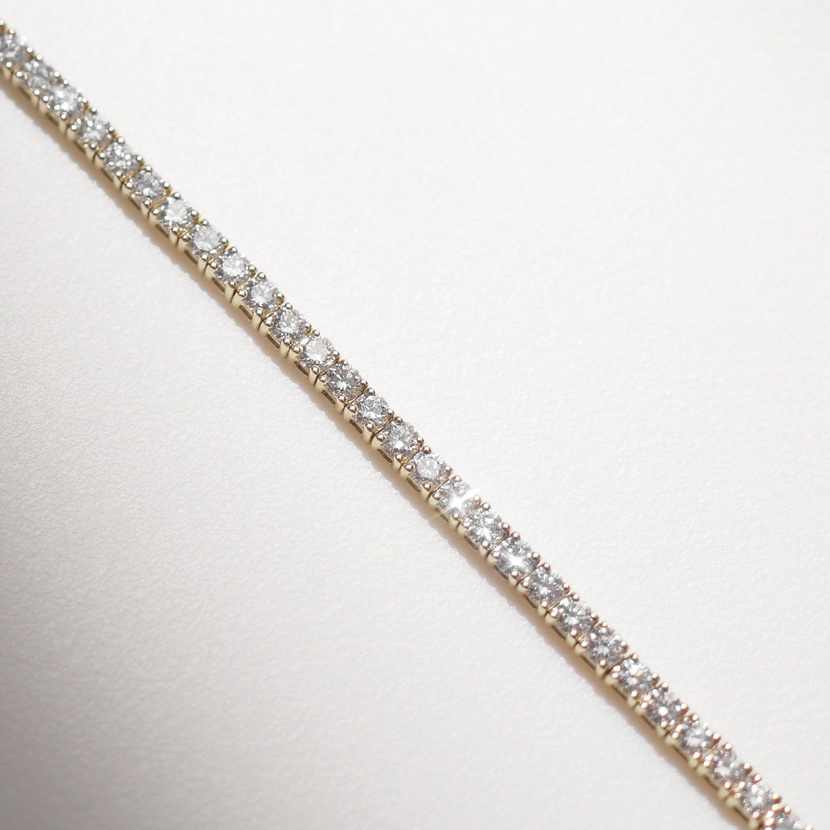 Diamond bracelet on a white surface with a neutral background
