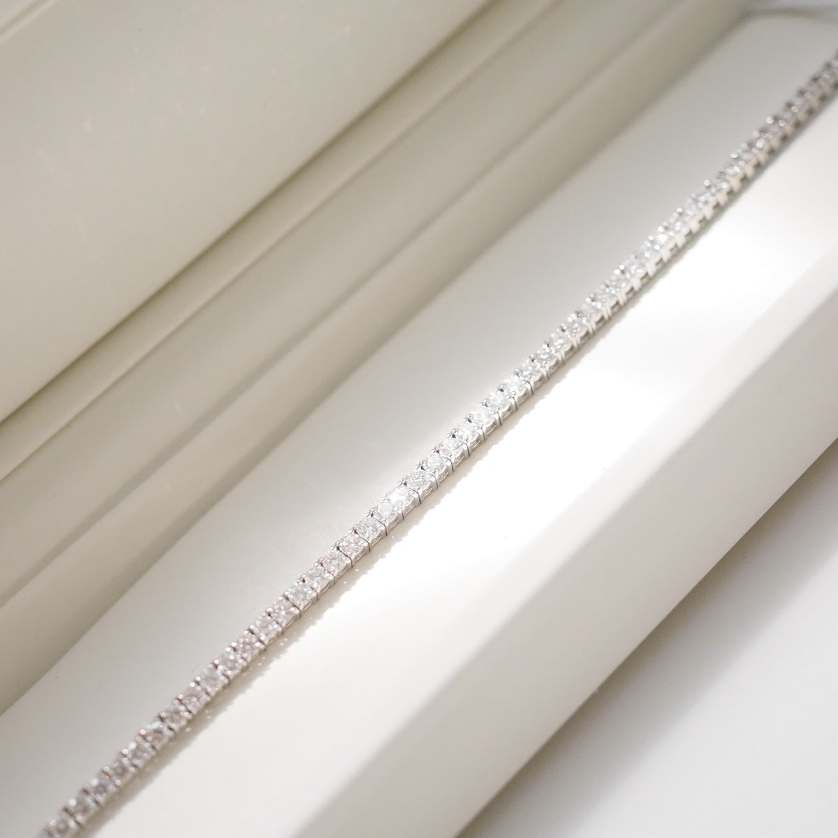 Diamond bracelet on a white surface with a neutral background