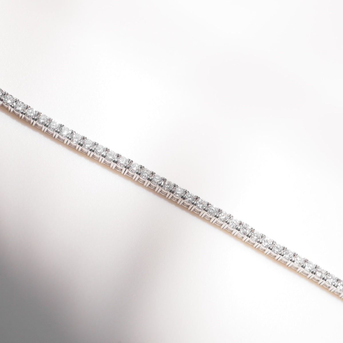 Diamond bracelet on a white surface with a neutral background