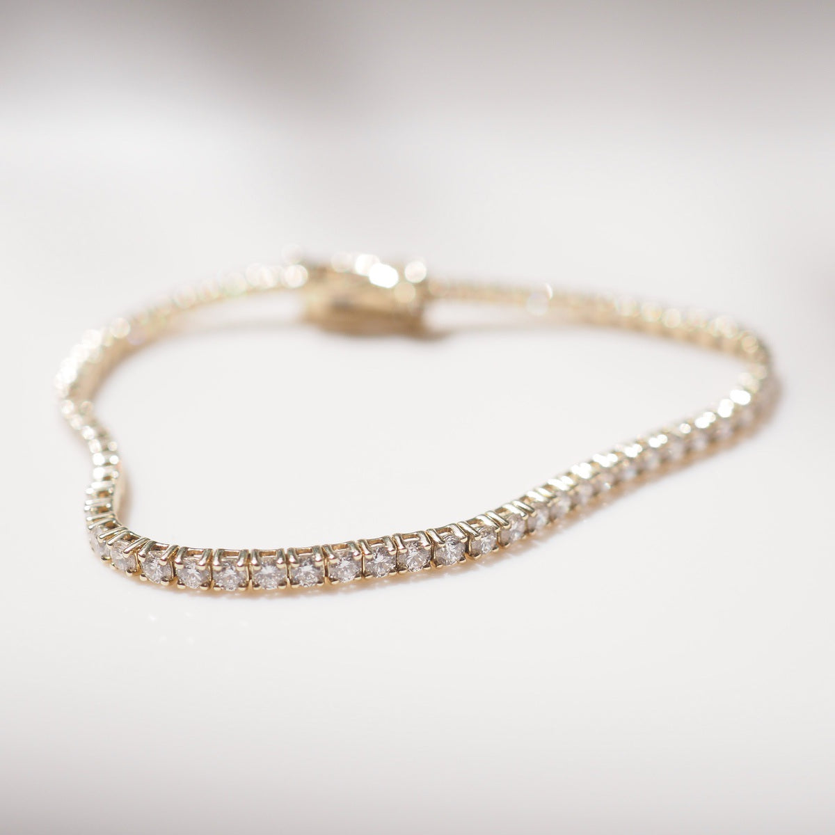 Diamond bracelet on a white surface with a neutral background