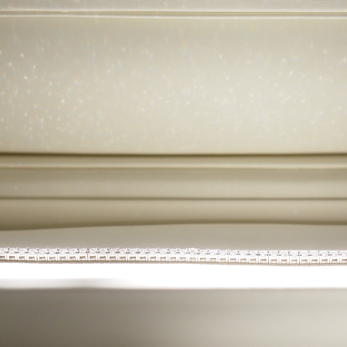 Diamond bracelet on a white surface with a neutral background