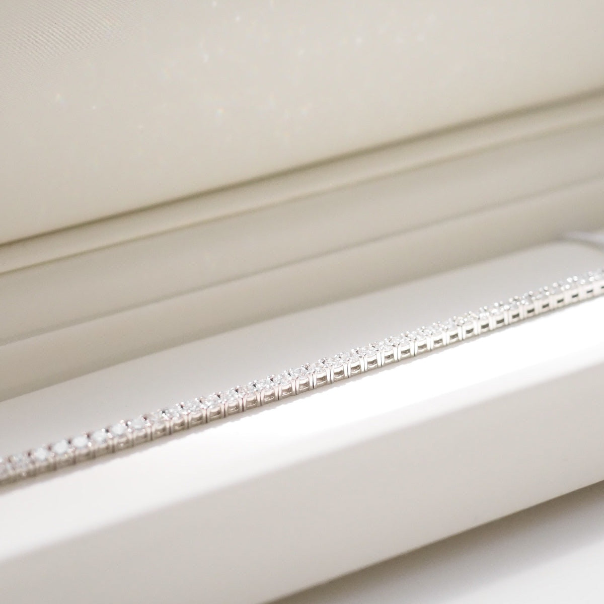 Diamond bracelet on a white surface with a neutral background