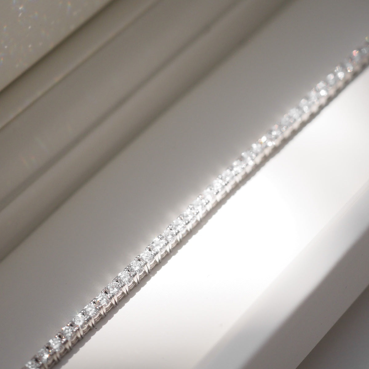 Diamond bracelet on a white surface with a neutral background