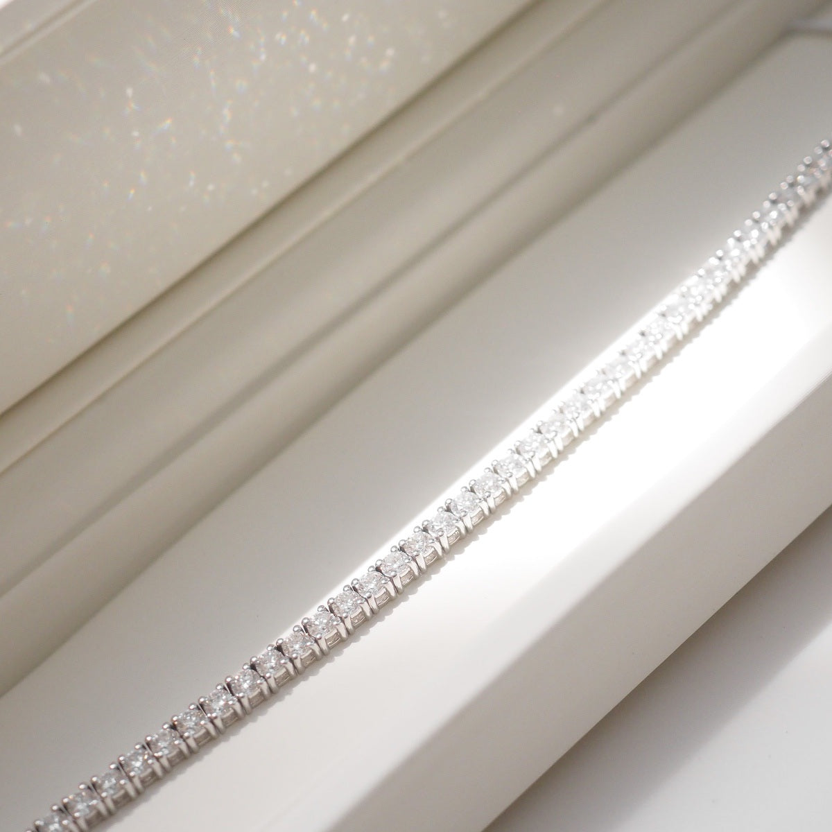 Diamond bracelet on a white surface with a neutral background