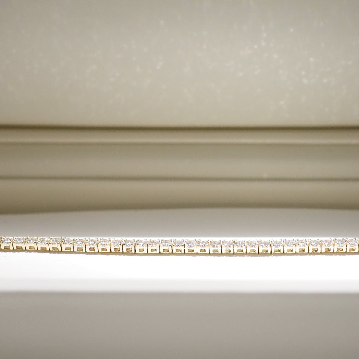 Diamond bracelet on a white surface with a neutral background