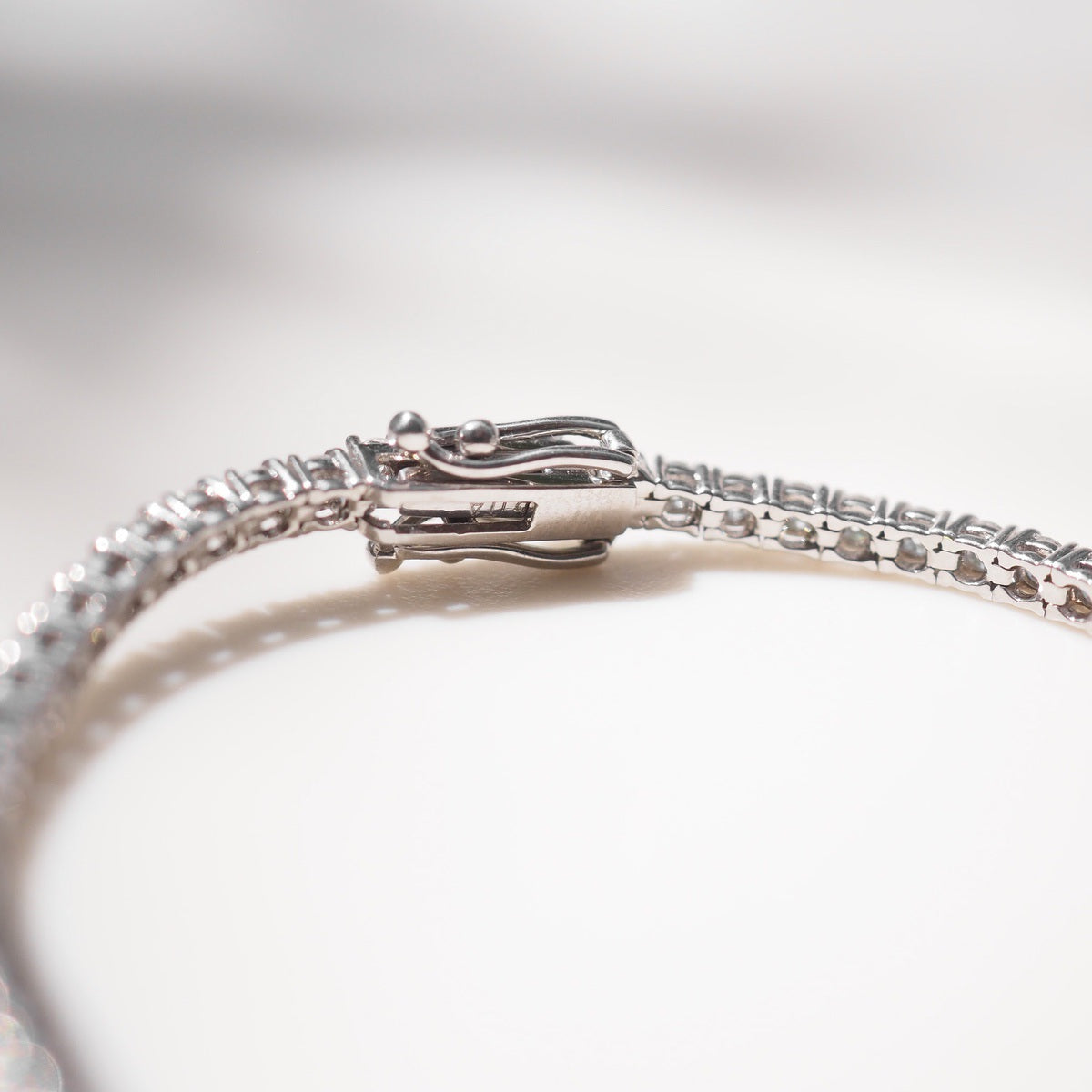 Diamond bracelet on a white surface with a neutral background