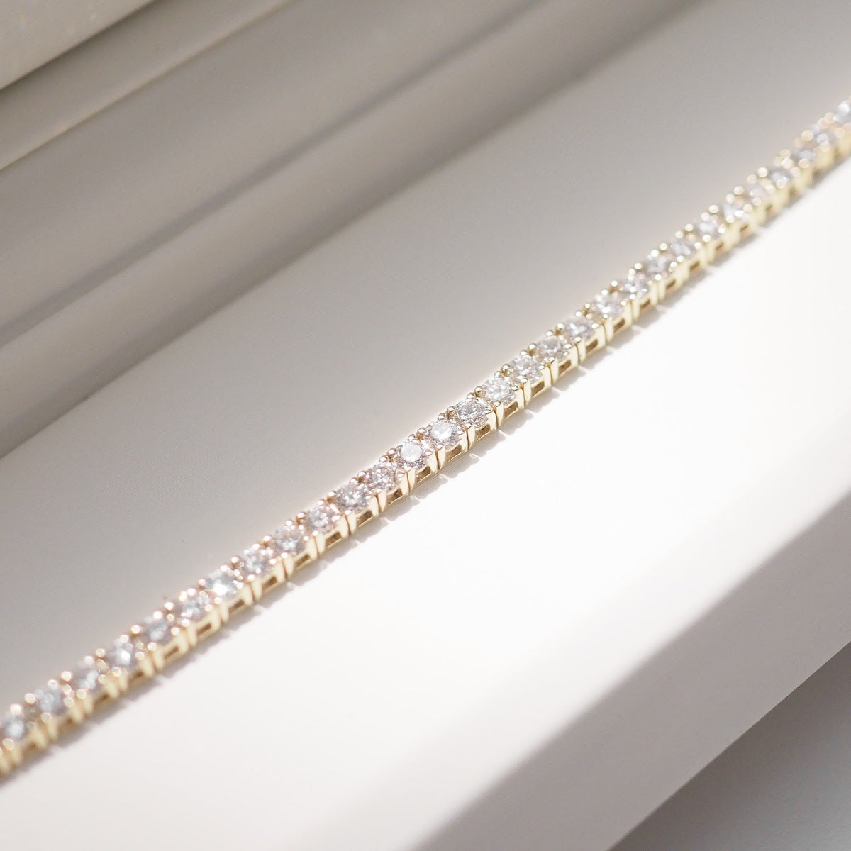 Diamond bracelet on a white surface with a neutral background