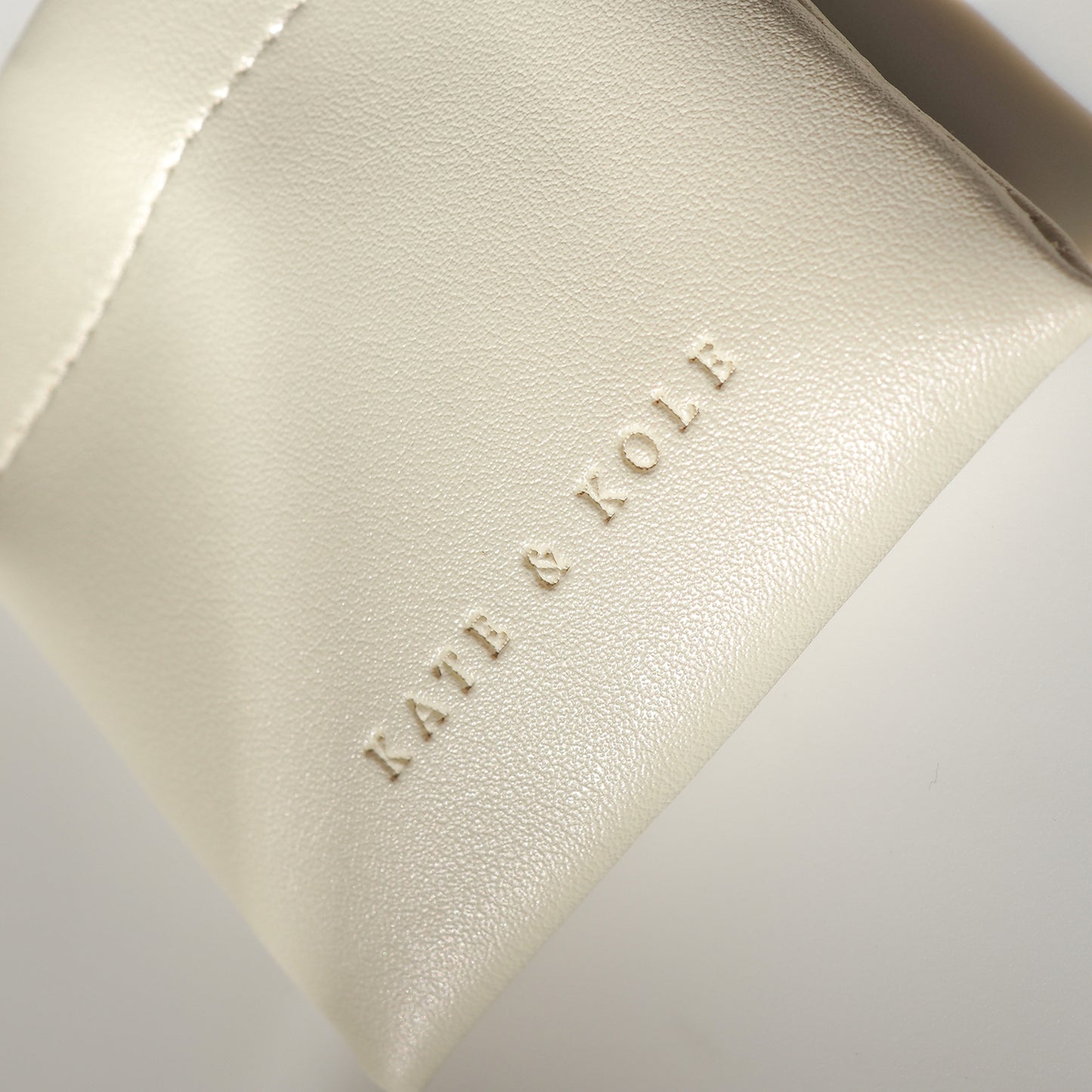 Cream leather jewellery pouch with embossed "KATE & KOLE" branding, showcasing luxury design and elegance.