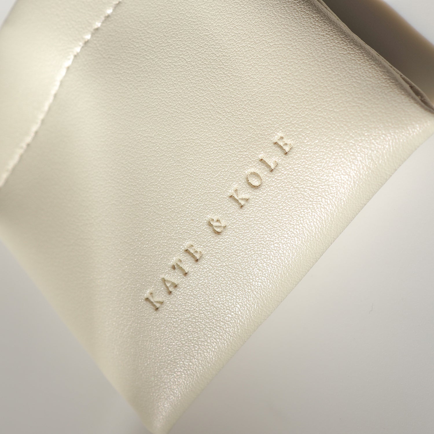 Cream leather jewellery pouch with embossed "KATE & KOLE" branding, showcasing luxury design and elegance.