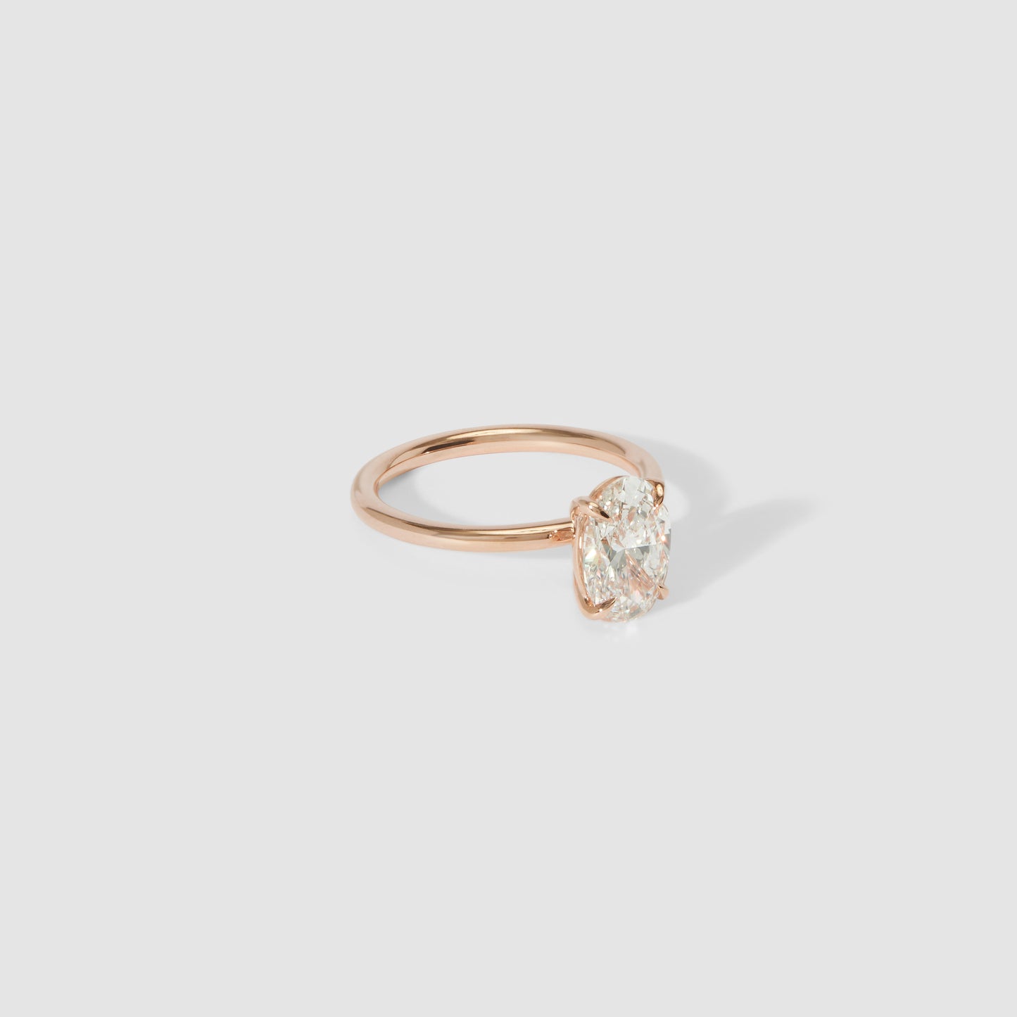 Elegant gold ring with an oval diamond solitaire on a clean grey background. Perfect for luxury jewellery lovers.