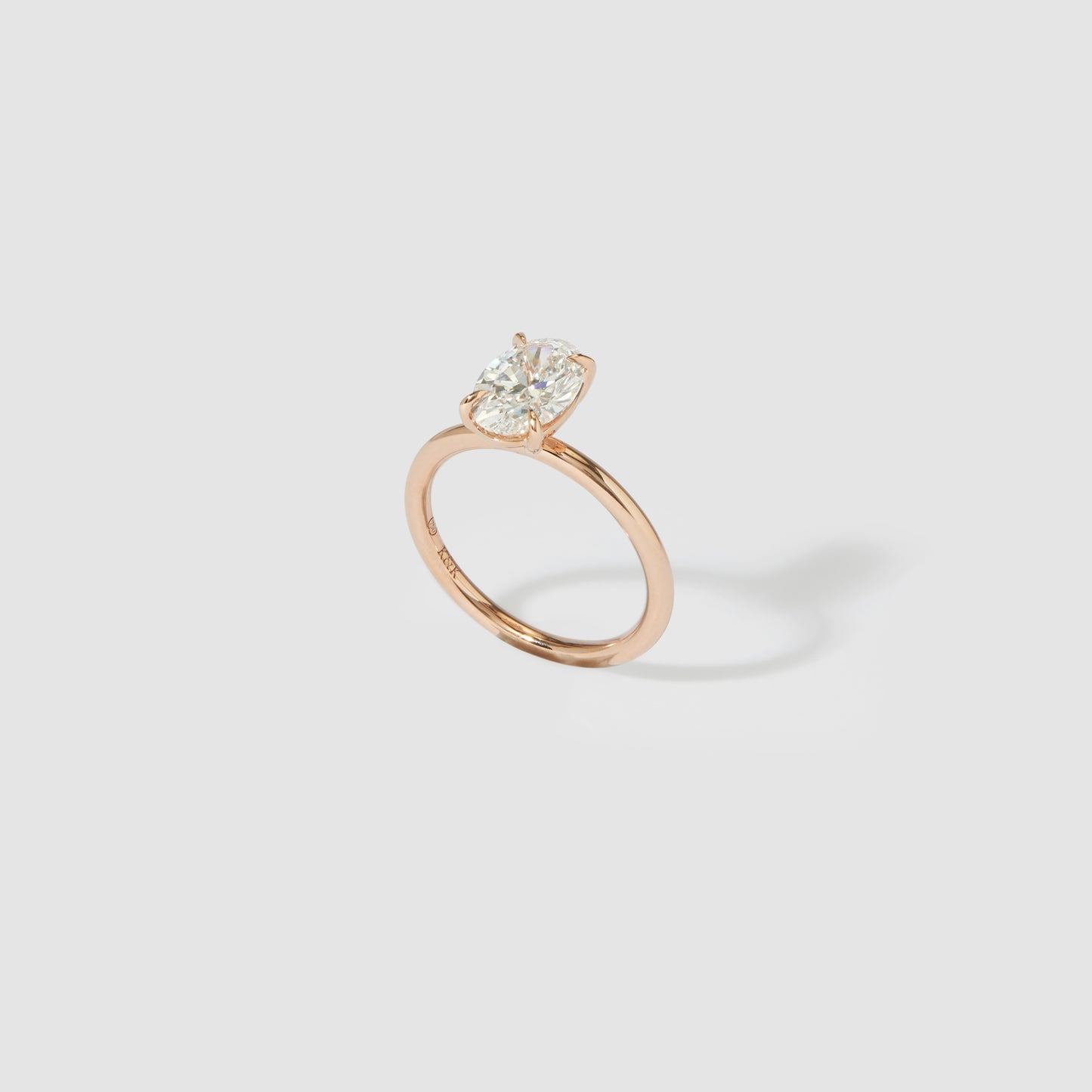 Rose gold ring with a large oval diamond solitaire on a light grey background. Luxurious, elegant jewellery design.