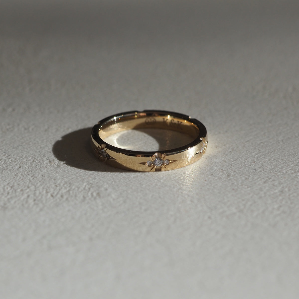 A solid 18ct yellow gold half-round band, set with six tiny trios of speciality set lab-grown diamonds. 3mm thick