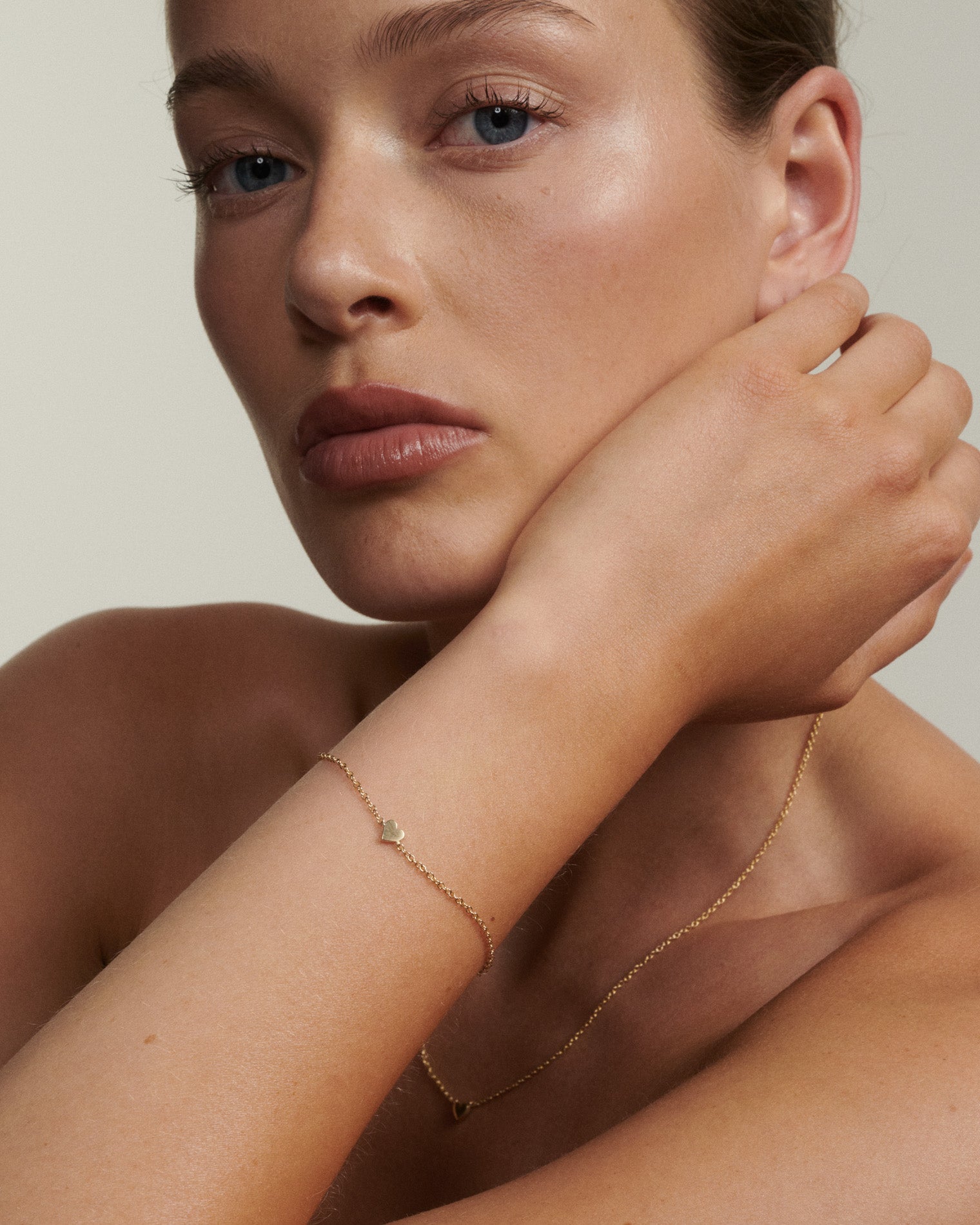 Woman wearing gold jewelry against a neutral background