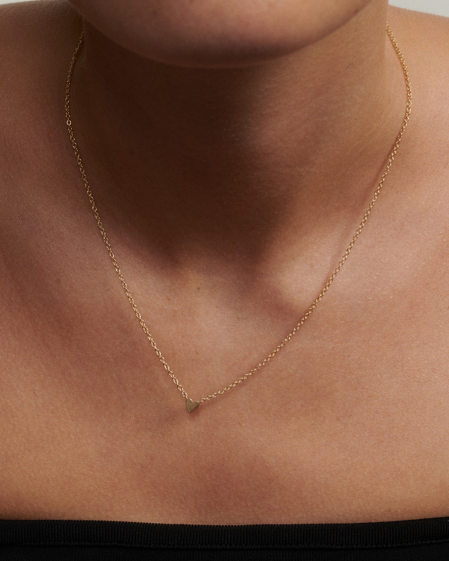 Gold necklace on a person's neck with a plain background