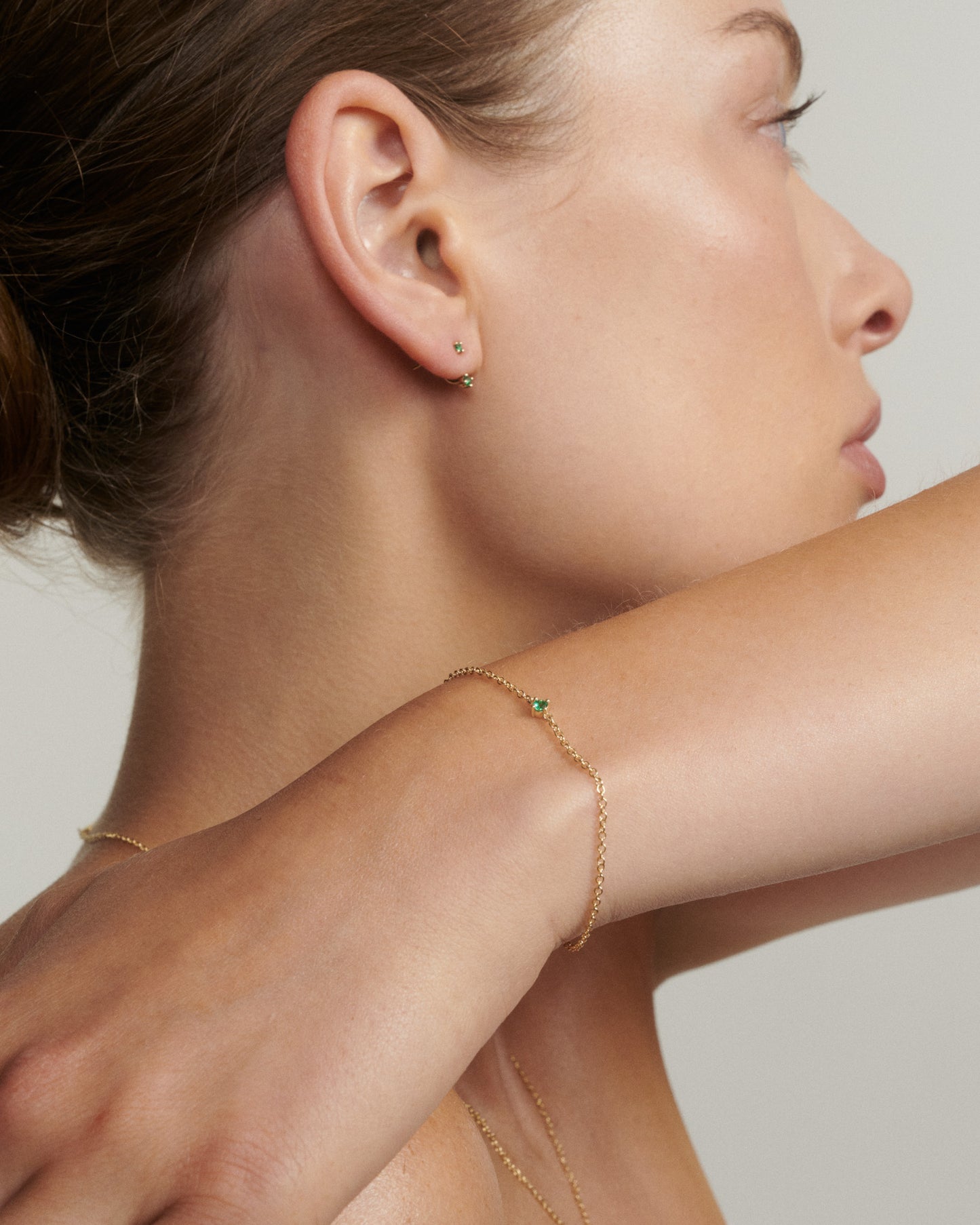 Close-up of a woman wearing gold jewelry on a neutral background