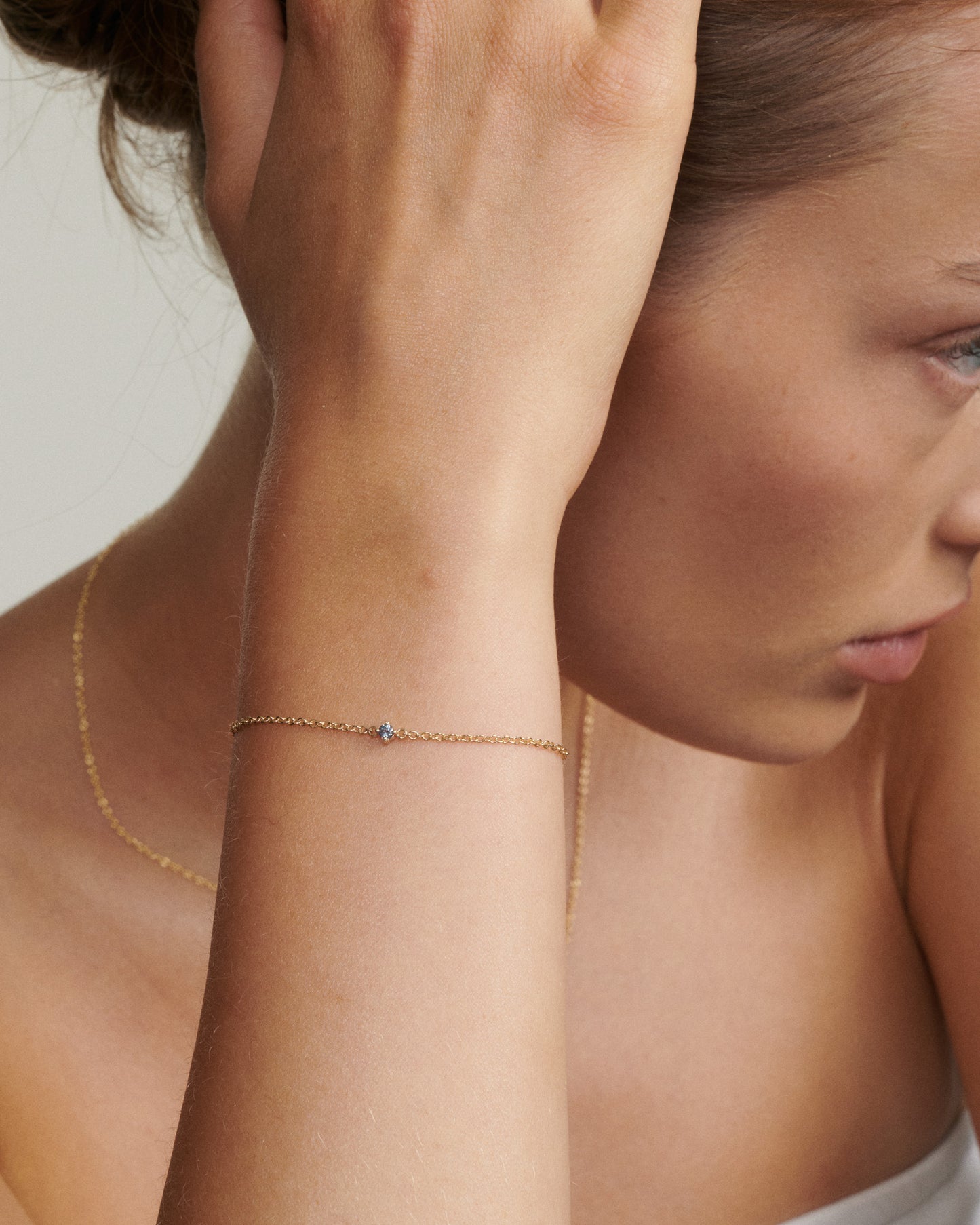 Close-up of a woman wearing a delicate gold necklace with a small pendant.