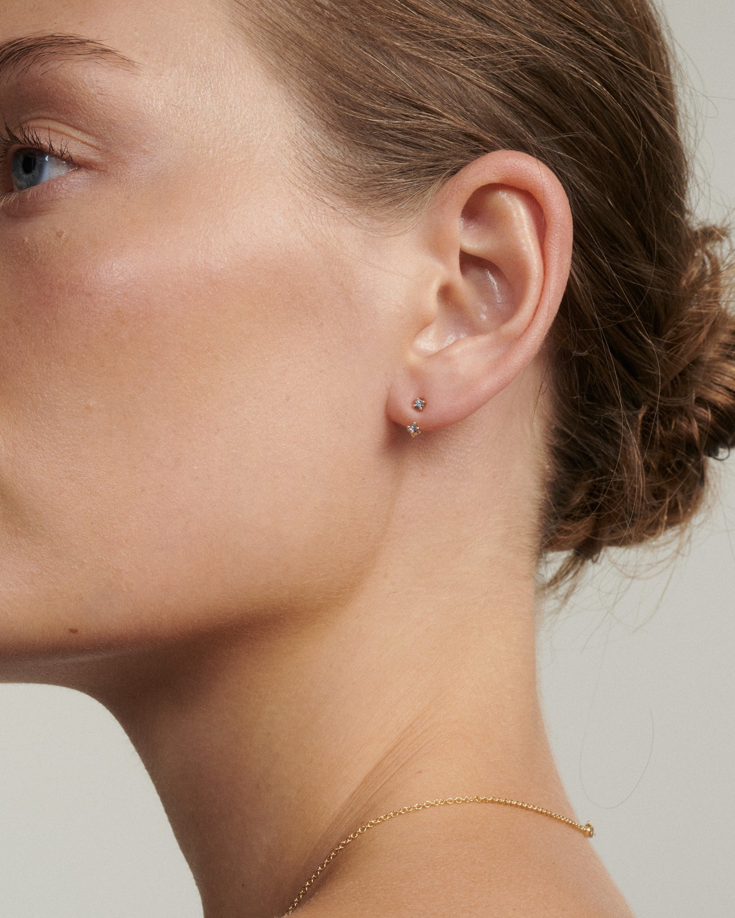 Close-up of a person wearing a small earring with a neutral background