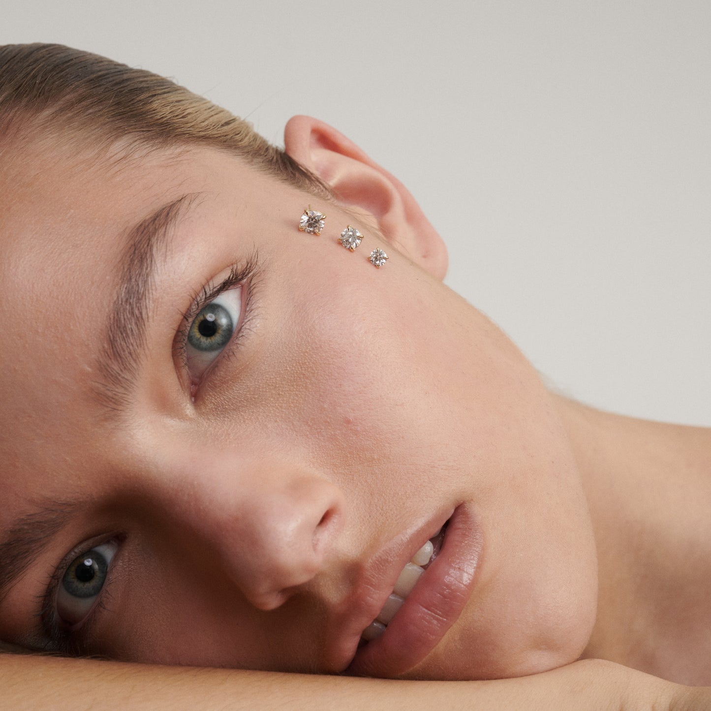 Close-up of a person with decorative earrings on a neutral background
