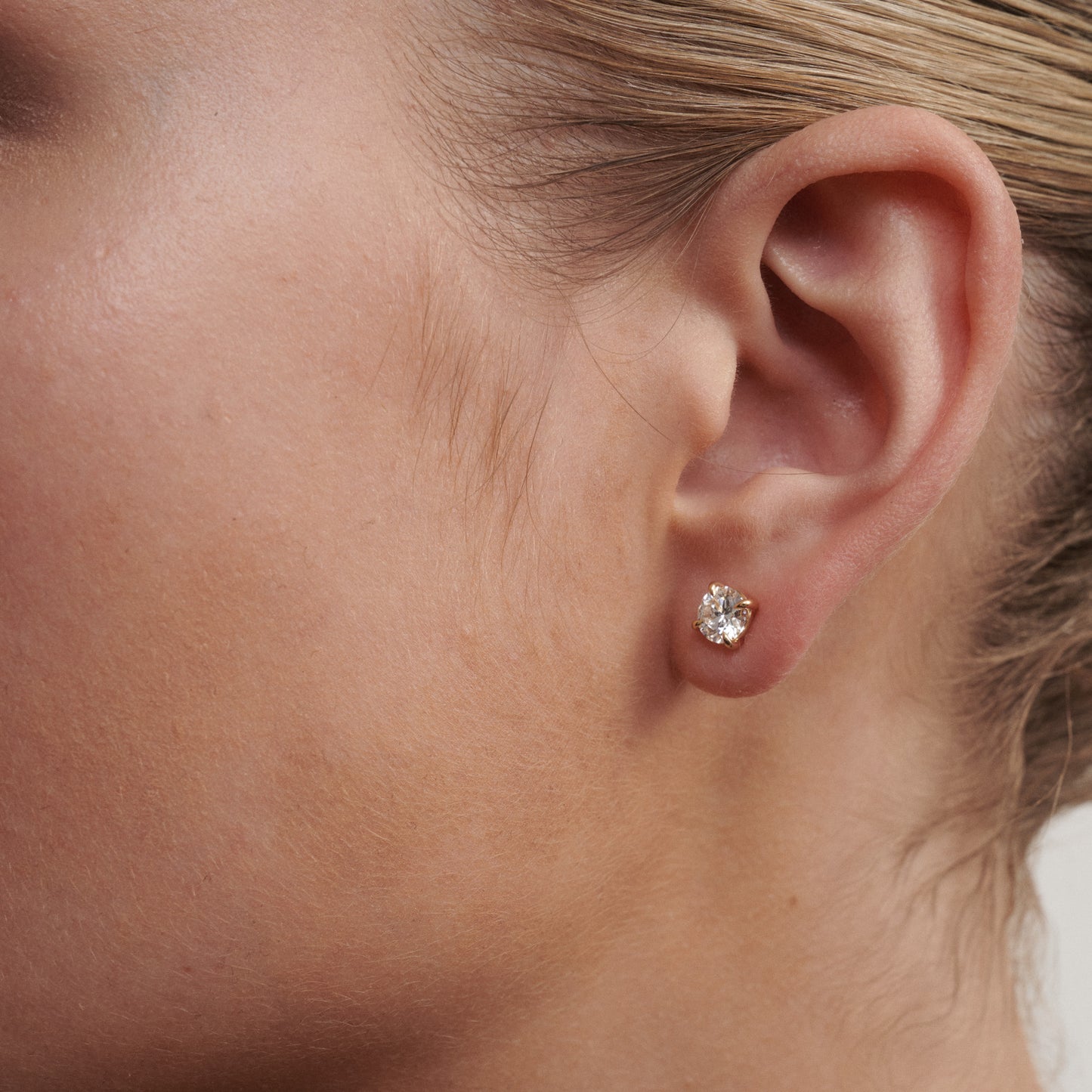 Close-up of an ear wearing a diamond stud earring.