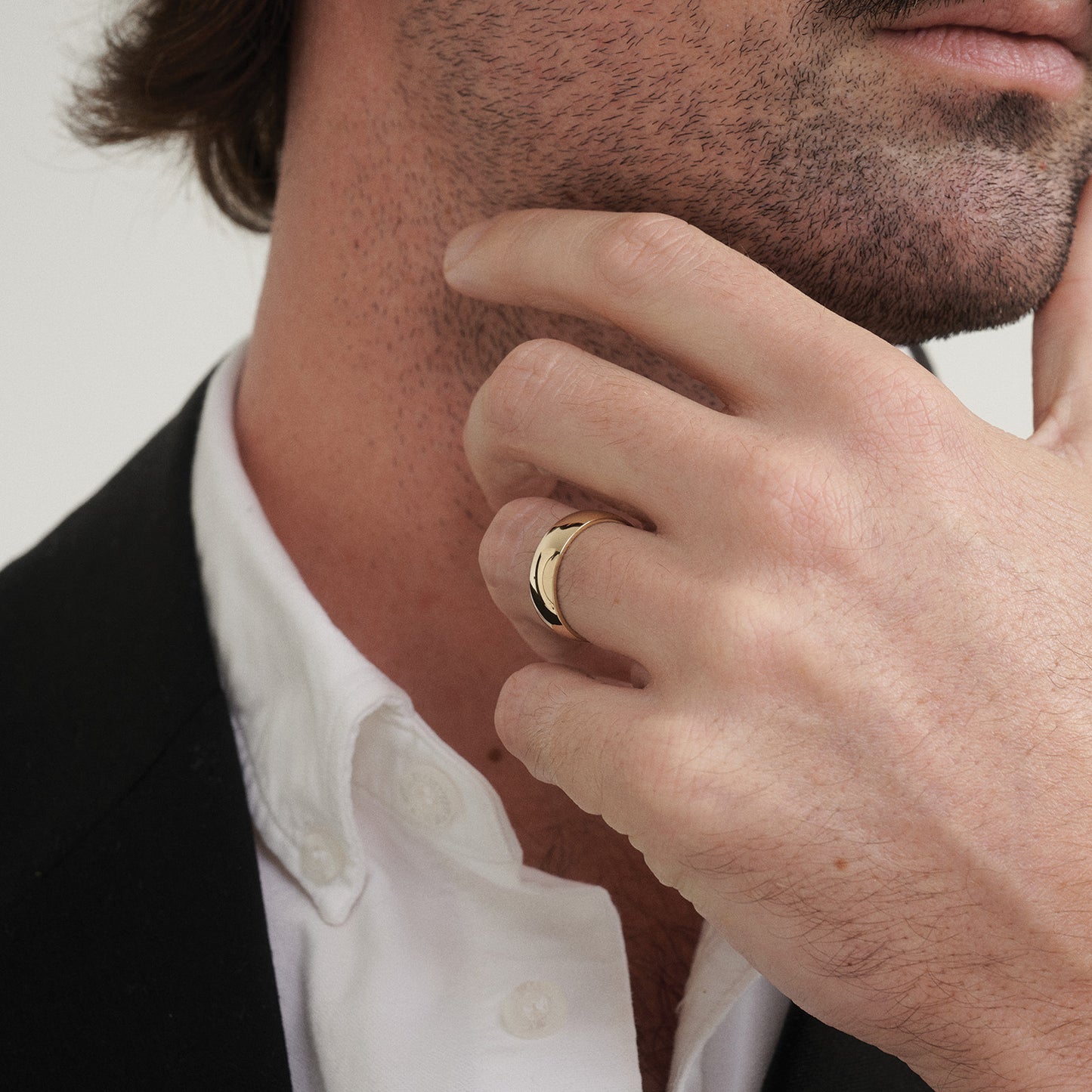 Man wearing a gold ring on his finger, close-up of hand and neck.
