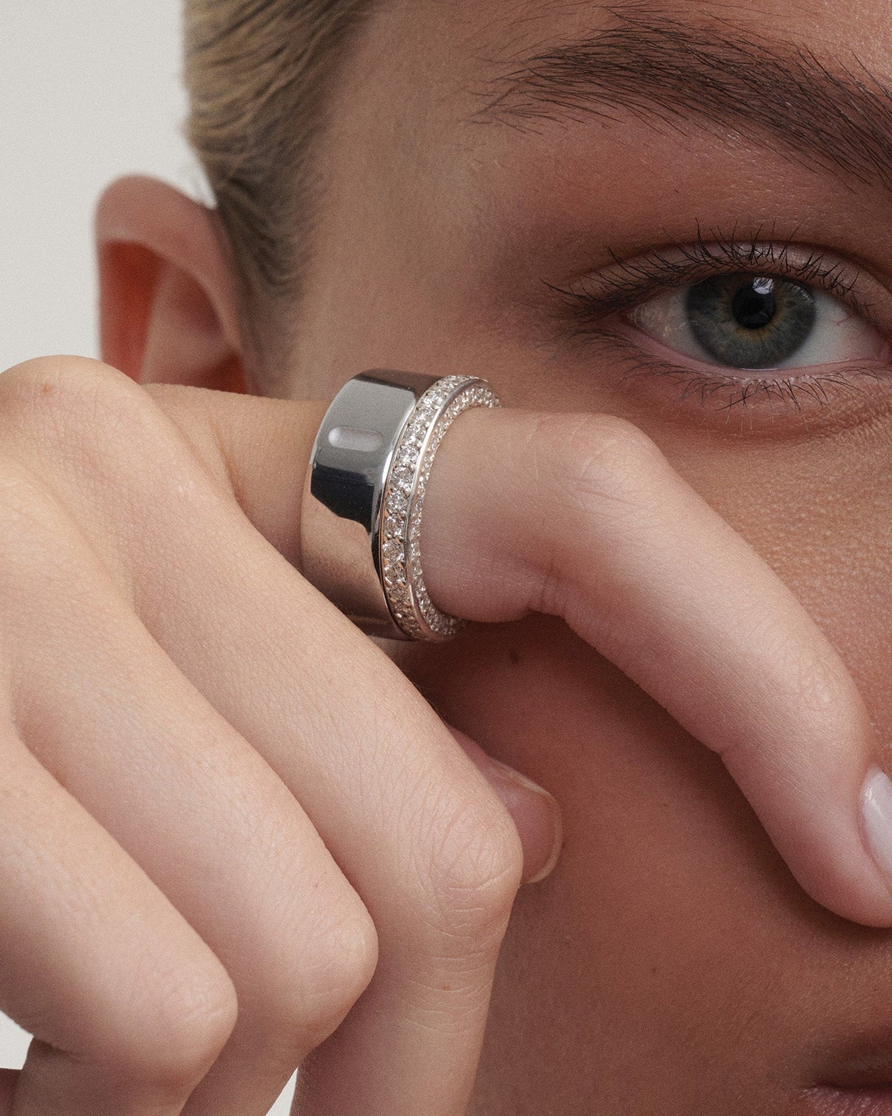 Close-up of a person wearing a white gold  ring on their finger alongside their Oura Ring  [text overlay: ]