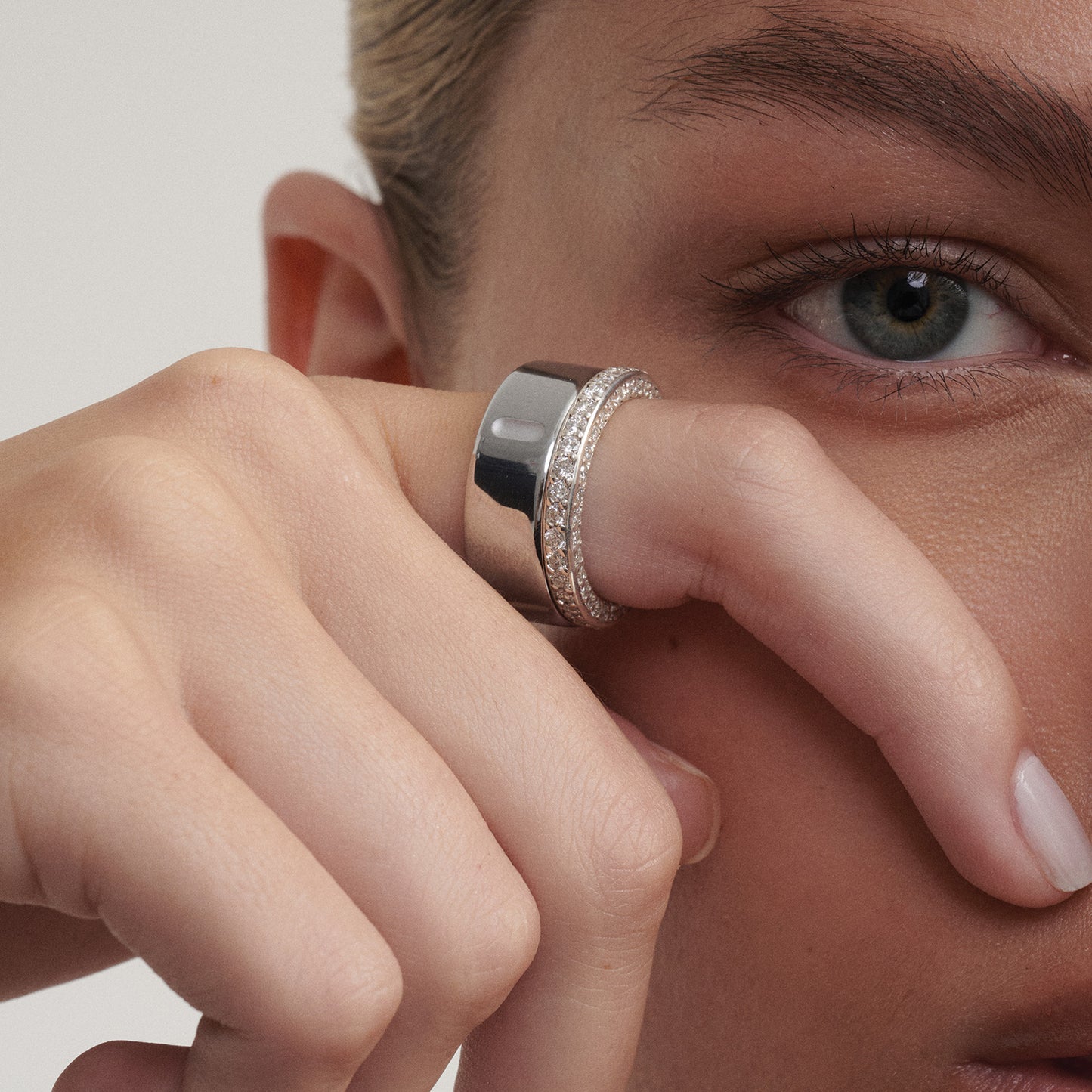 Close-up of a person wearing a white gold  ring on their finger alongside their Oura Ring