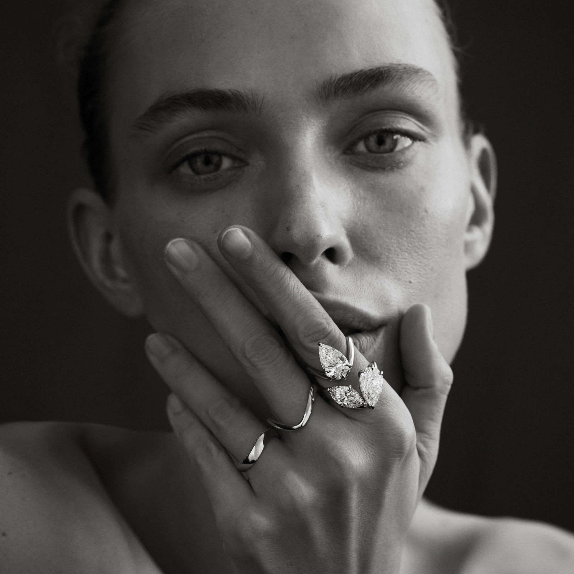 Black and white portrait of a person wearing diamond jewelry with a dark background