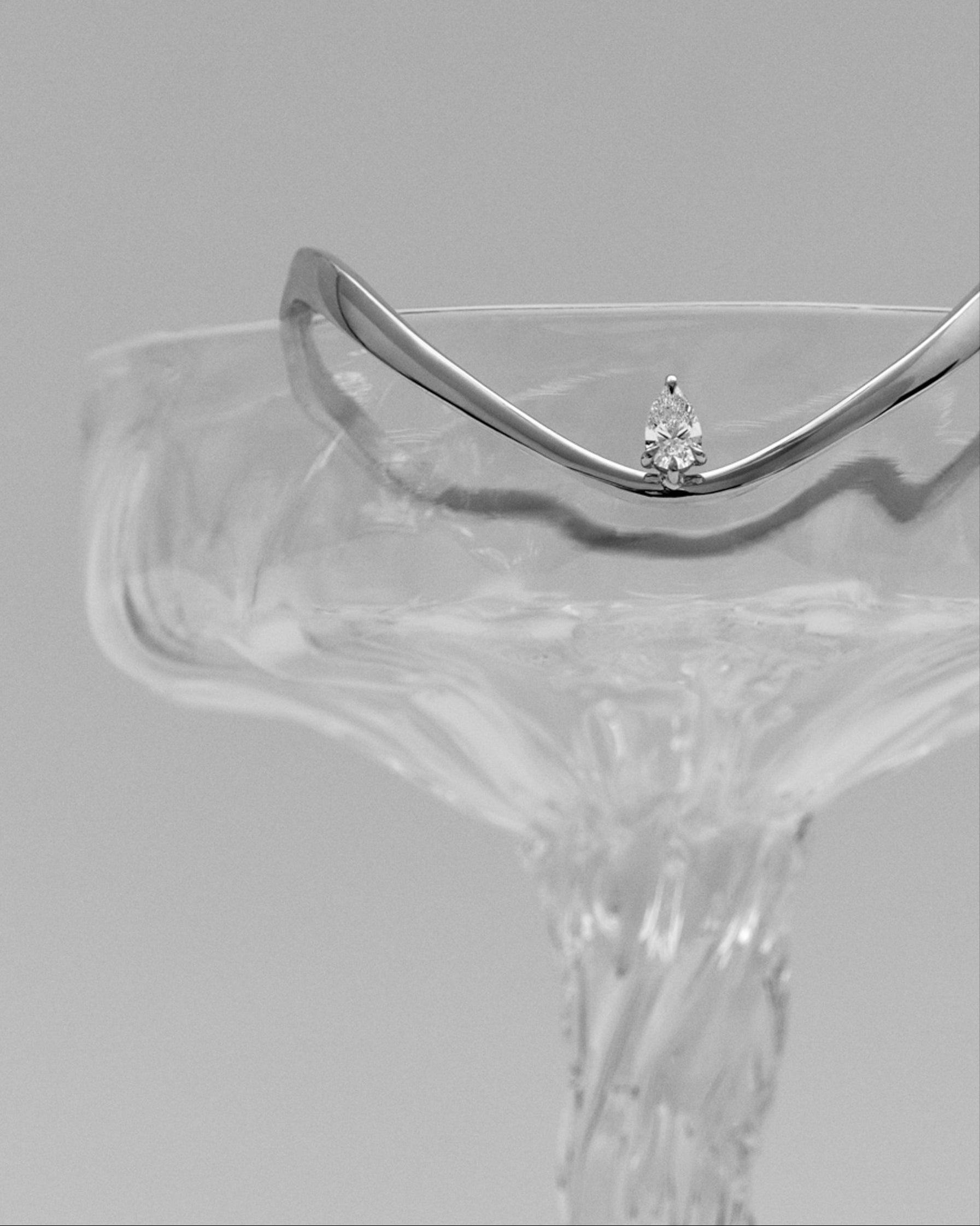 Silver bracelet with a diamond on a clear stand against a gray background