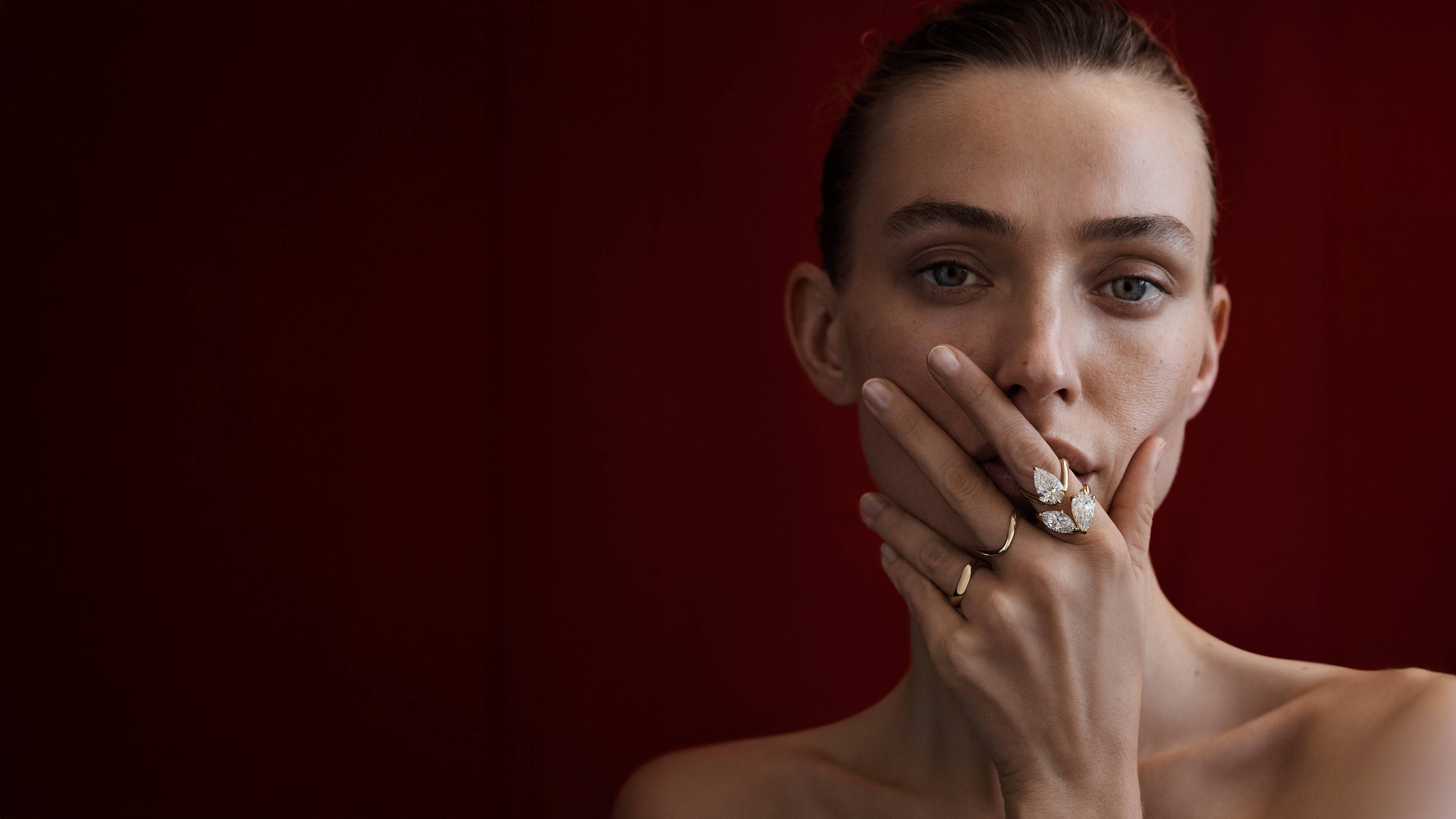 Woman with a ring on her finger against a red background