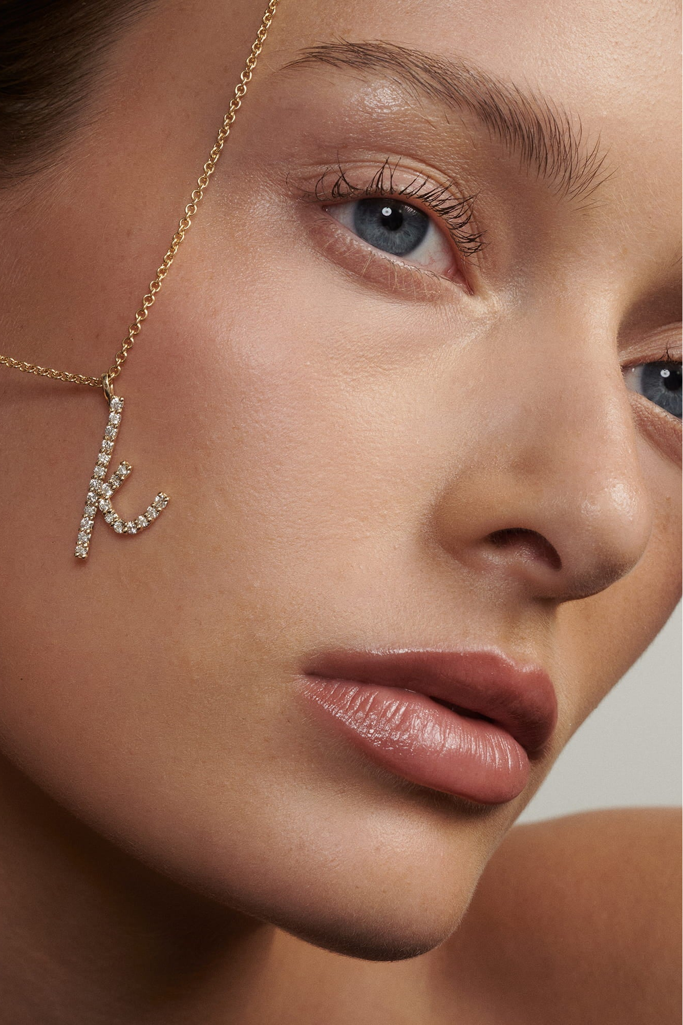 Close-up of a woman's face with a gold 'K' earring.